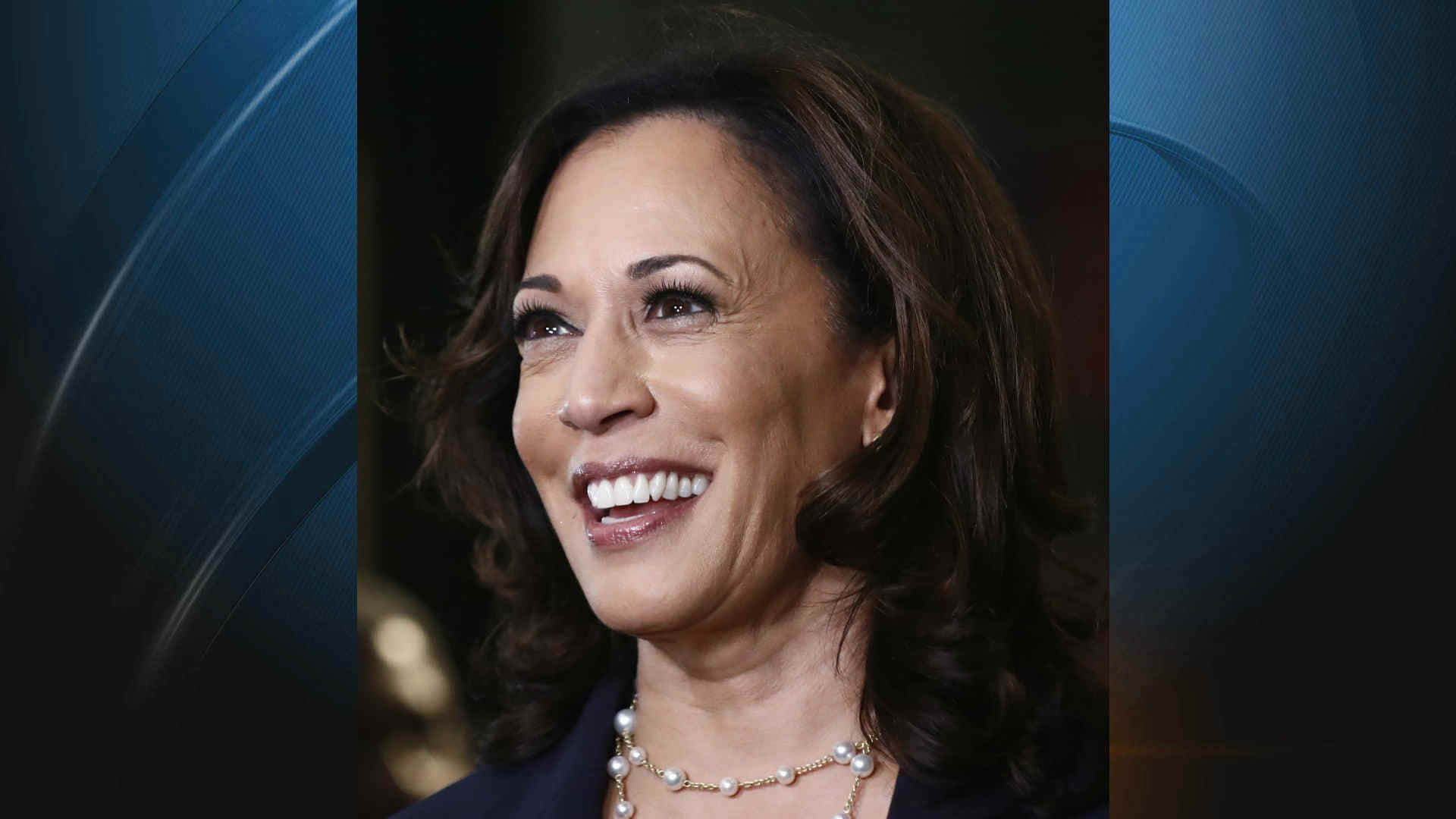 Kamala Harris 桌布 壁紙 — 卡瑪拉·哈里斯在深藍色抽象背景前溫暖微笑的特寫肖像。