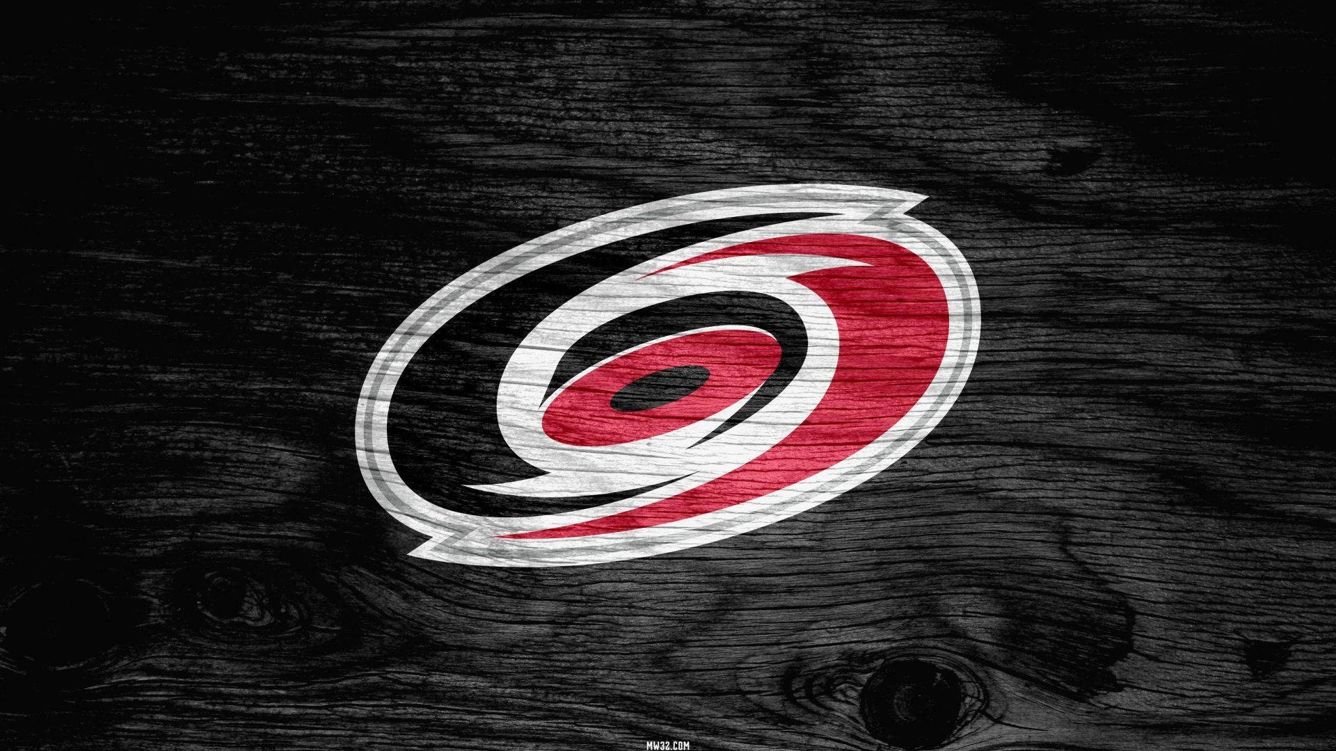 Hurricanes 桌布 壁紙 — 卡羅萊納颶風隊的紅白黑標誌放置在深色紋理木質表面上。