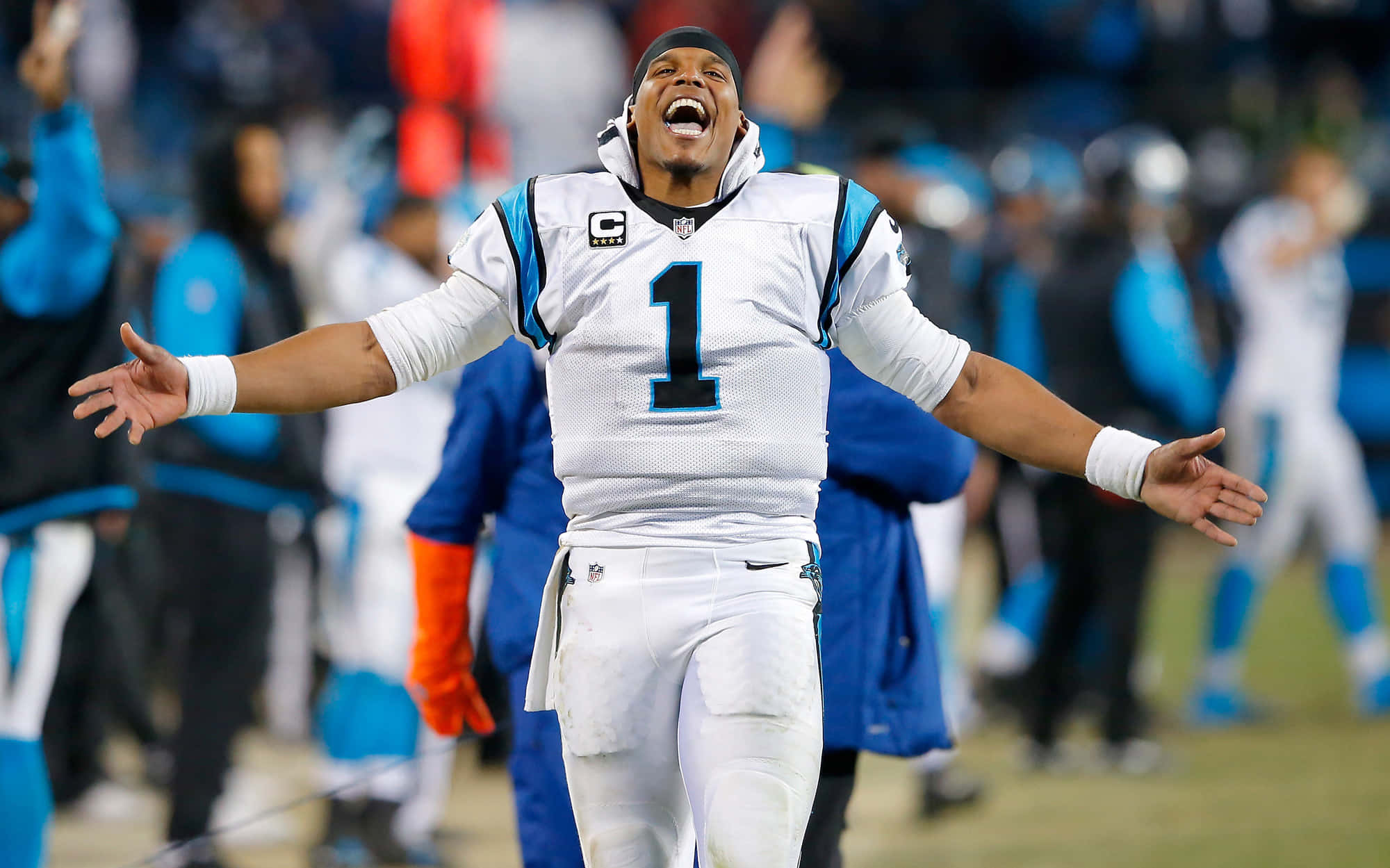 Cam Newton 桌布 壁紙 — 卡羅萊納黑豹隊的四分衛身穿白色一號球衣，在足球場上張開雙臂慶祝勝利。