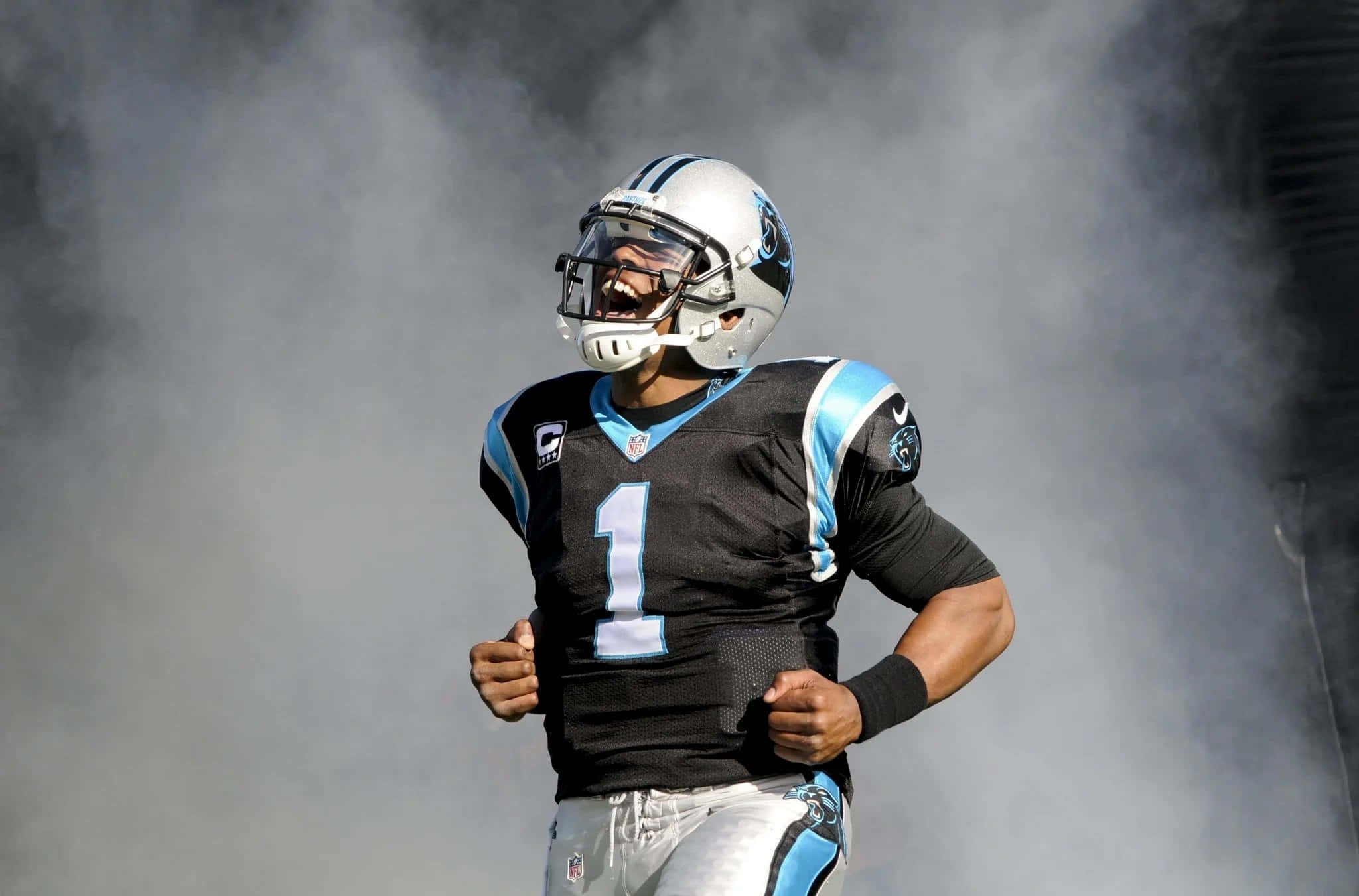 Cam Newton 桌布 壁紙 — 卡羅萊納黑豹隊的足球員身穿一號球衣，帶著強烈的專注和決心穿過煙霧奔跑。