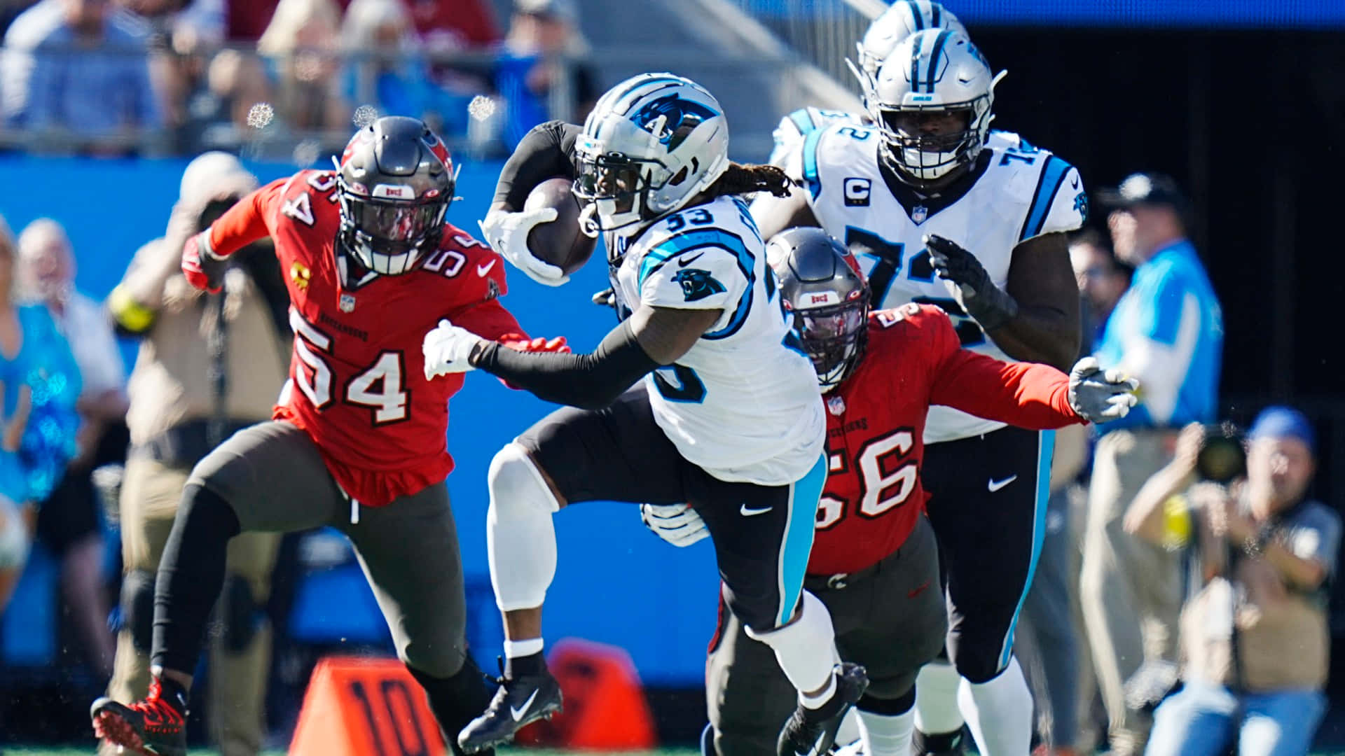 Carolina Panthers 桌布 壁紙 — 卡羅萊納黑豹隊的跑衛在明亮的日間NFL比賽中突破亞特蘭大獵鷹隊防守球員的擒抱。