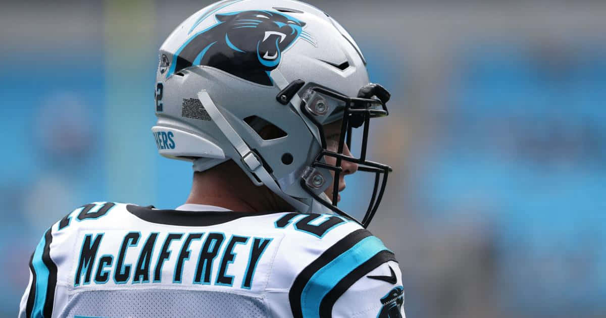 Christian Mccaffrey 桌布 壁紙 — 卡羅萊納黑豹隊美式足球員的近距離特寫，戴著銀色頭盔，身穿帶有藍色裝飾的白色球衣。