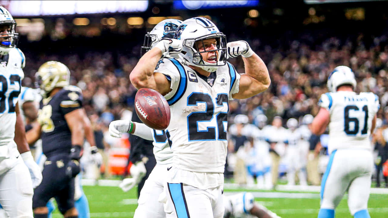 Christian Mccaffrey 桌布 壁紙 — 卡羅萊納黑豹隊身穿白色球衣的足球運動員在體育場燈光下高舉雙臂持球慶祝達陣。