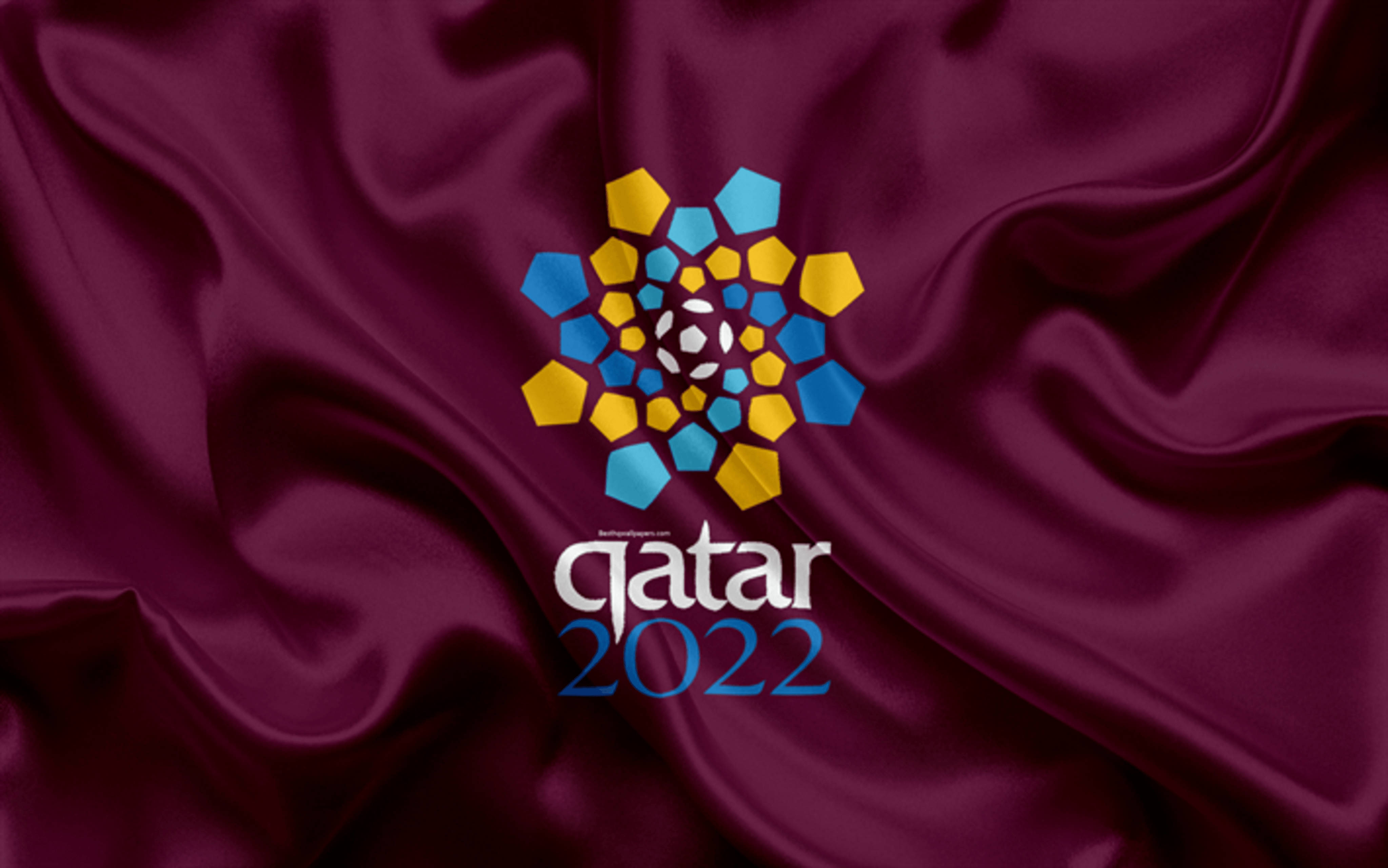 World 桌布 壁紙 — 卡達2022世界盃標誌在豐富的栗色緞面布料背景上以鮮豔的藍色和金色六邊形閃耀。