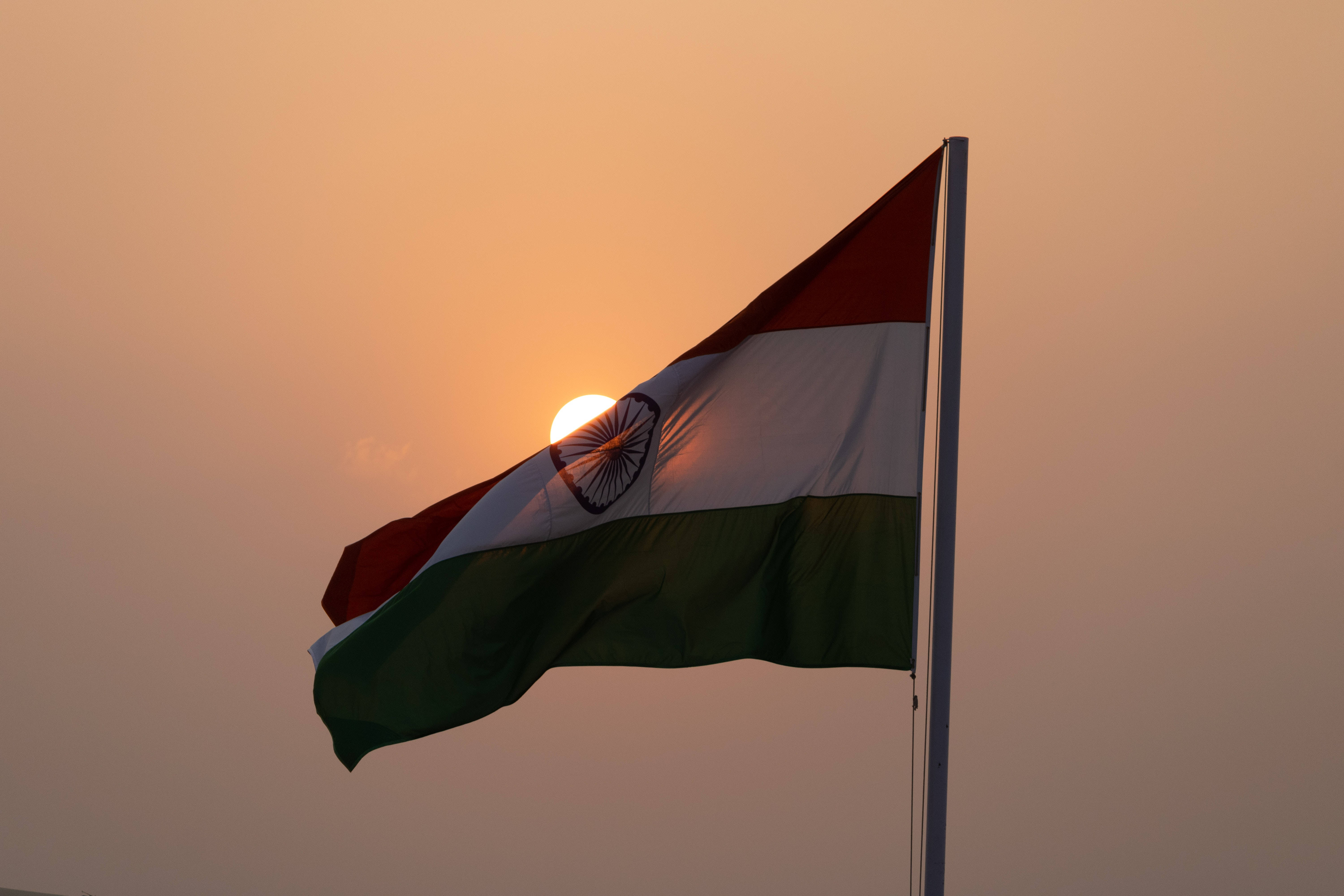 Indian 桌布 壁紙 — 印度國旗在溫暖的日落天空下自豪地飄揚，太陽在其中心後方閃耀。