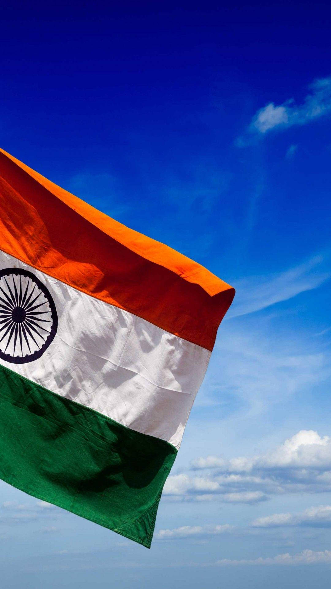 India 桌布 壁紙 — 印度國旗在藍天白雲下自豪地飄揚。