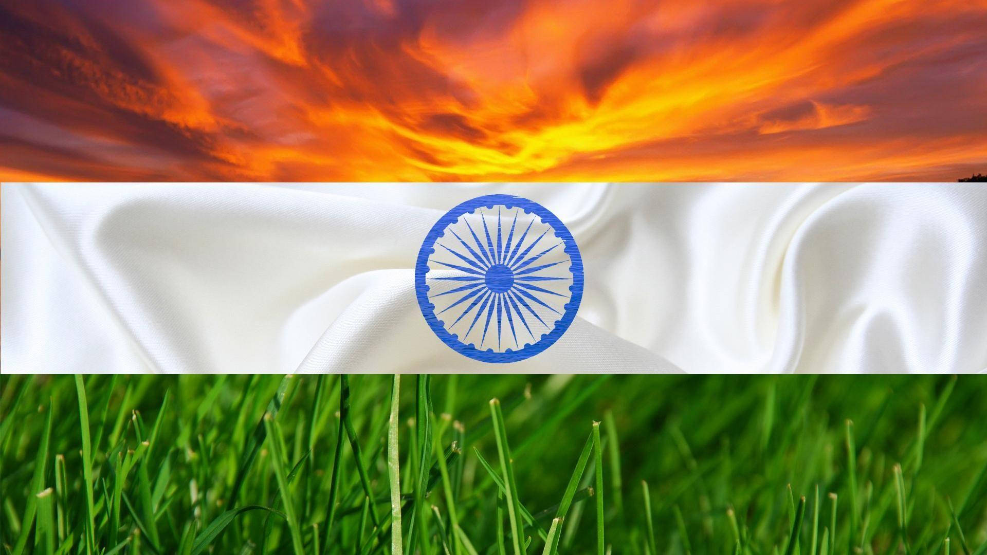 Flag 桌布 壁紙 — 印度國旗鋪在草地上，背景是熾熱的夕陽天空和鮮豔的橙色雲彩。