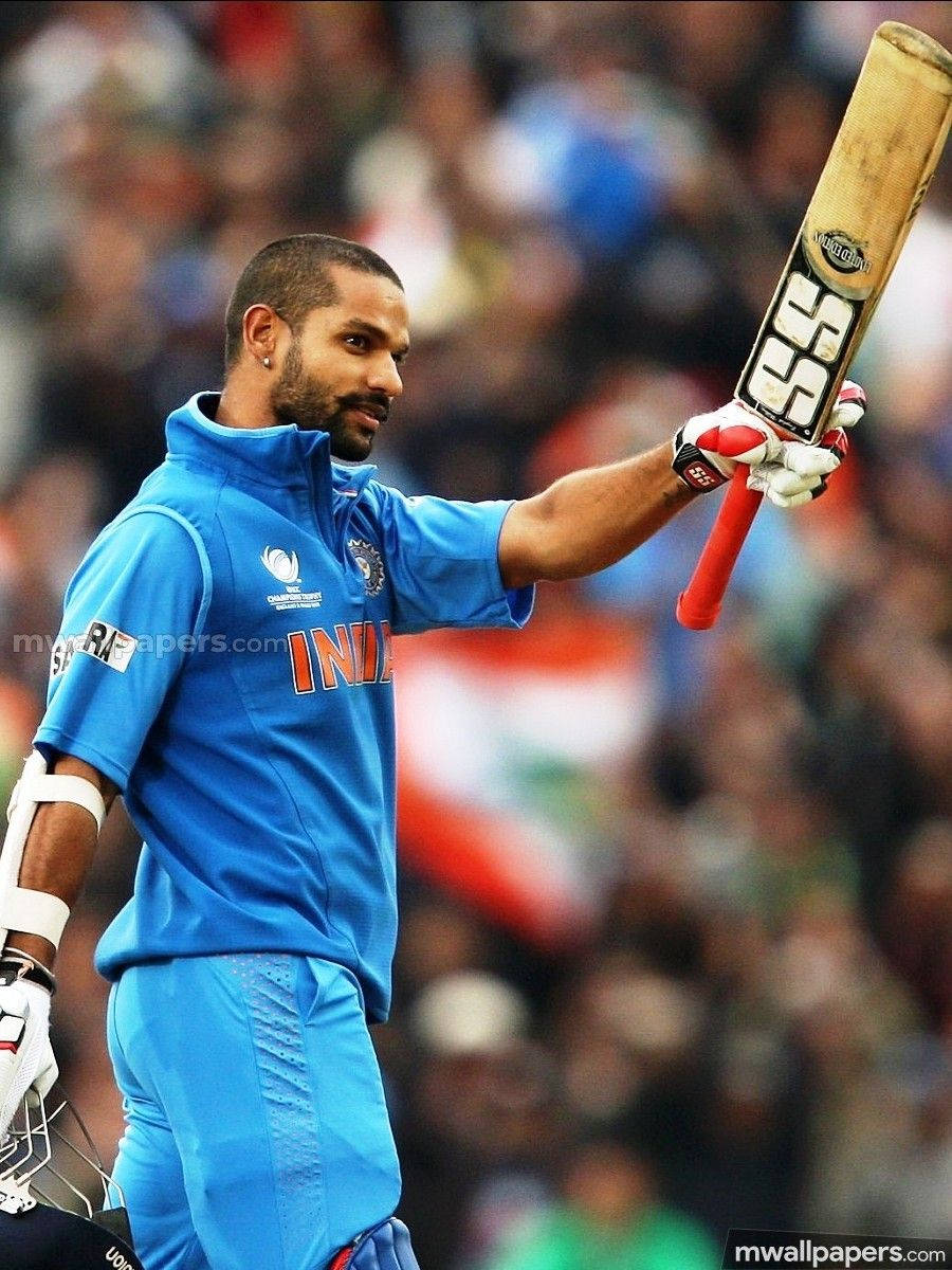 shikhar dhawan 桌布 壁紙 — 印度板球運動員在日間比賽中於體育場人群中高舉球棒。