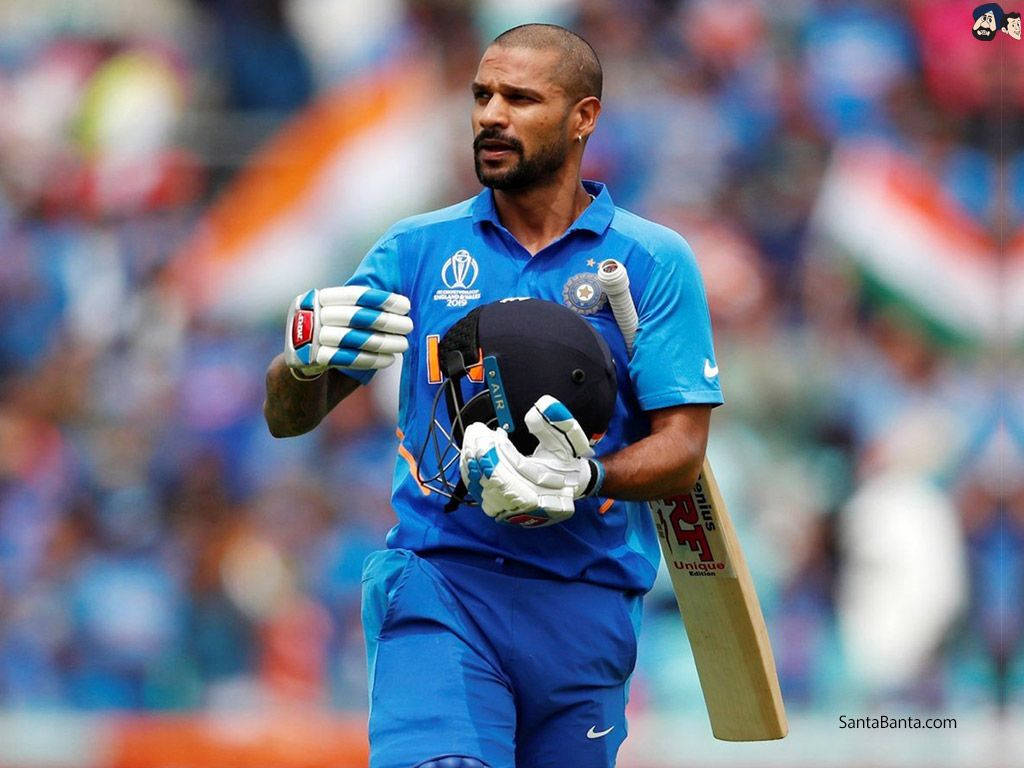 shikhar dhawan 桌布 壁紙 — 印度板球運動員在日間比賽中穿著藍色制服，手持球棒和頭盔離開球場。