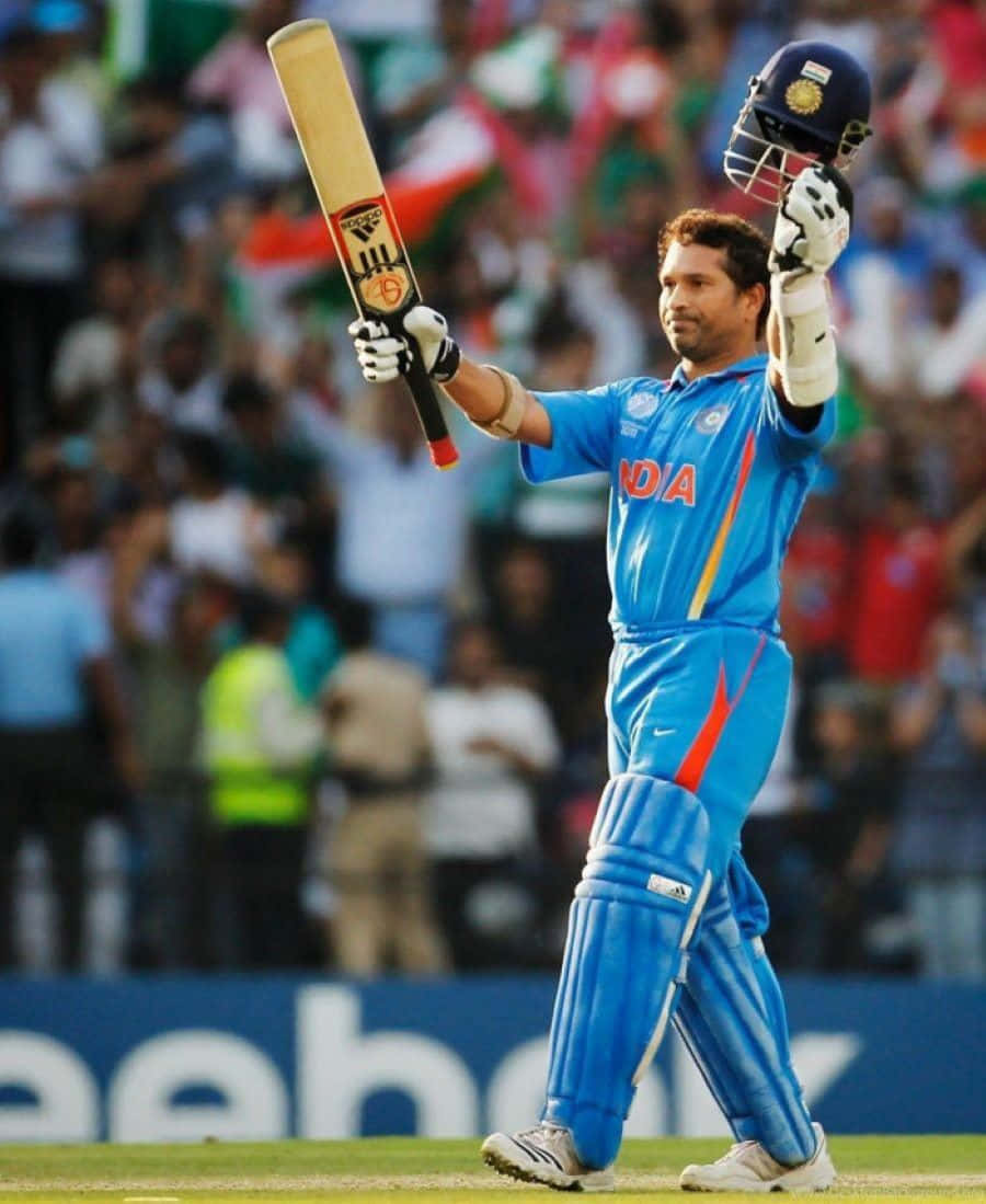 Sachin Tendulkar 桌布 壁紙 — 印度板球運動員在球場上高舉球棒和頭盔，在歡呼的人群面前勝利慶祝。