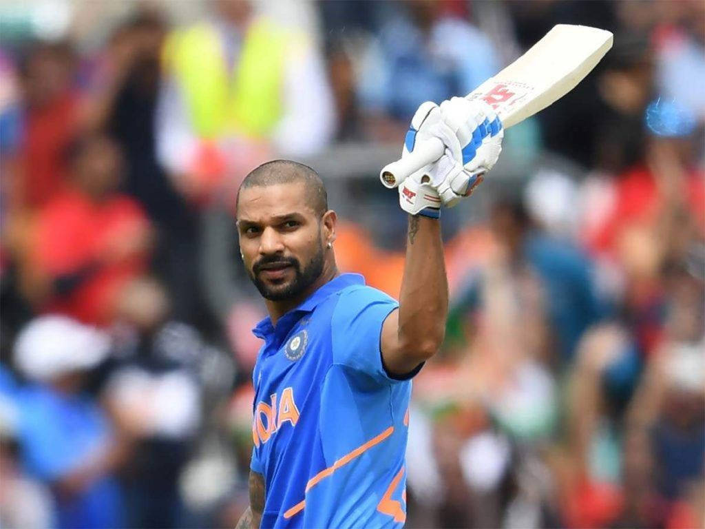 shikhar dhawan 桌布 壁紙 — 印度板球運動員在體育場內高舉球棒，在歡呼的人群前慶祝。