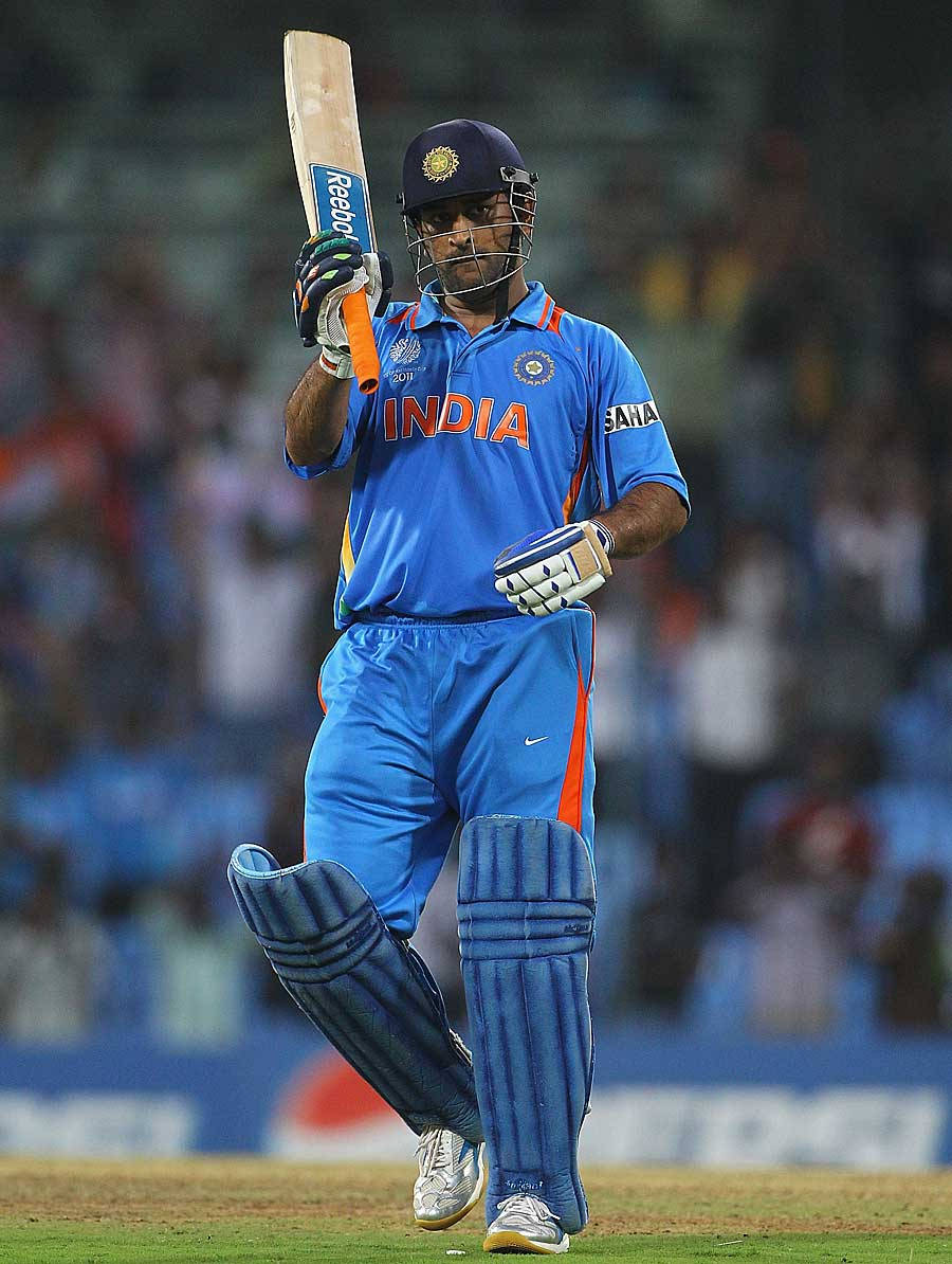 Ms Dhoni 桌布 壁紙 — 印度板球運動員身穿藍色制服，在夜間燈光球場上勝利地高舉球棒。