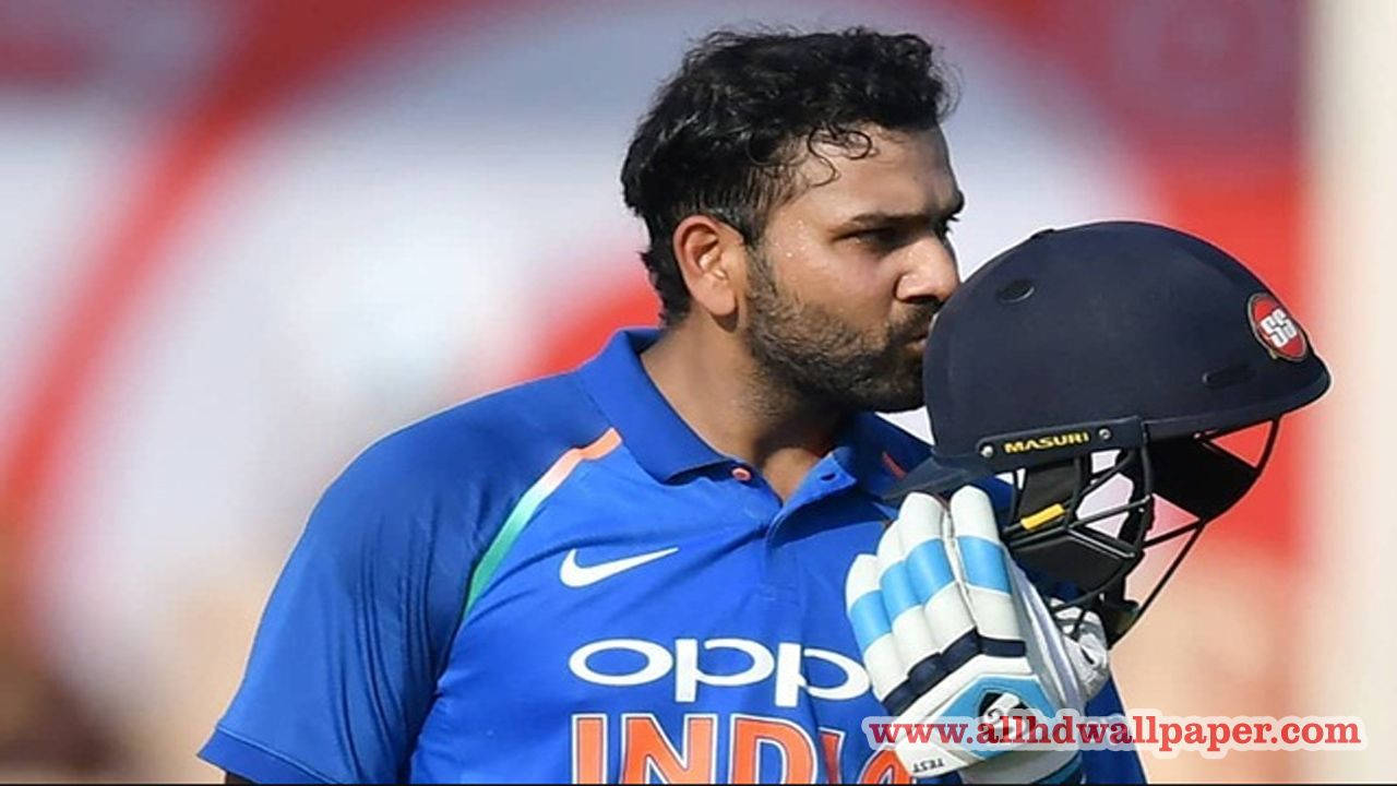 Rohit Sharma 桌布 壁紙 — 印度板球運動員身穿藍色球衣，在日間比賽中專注地拿著頭盔和手套。