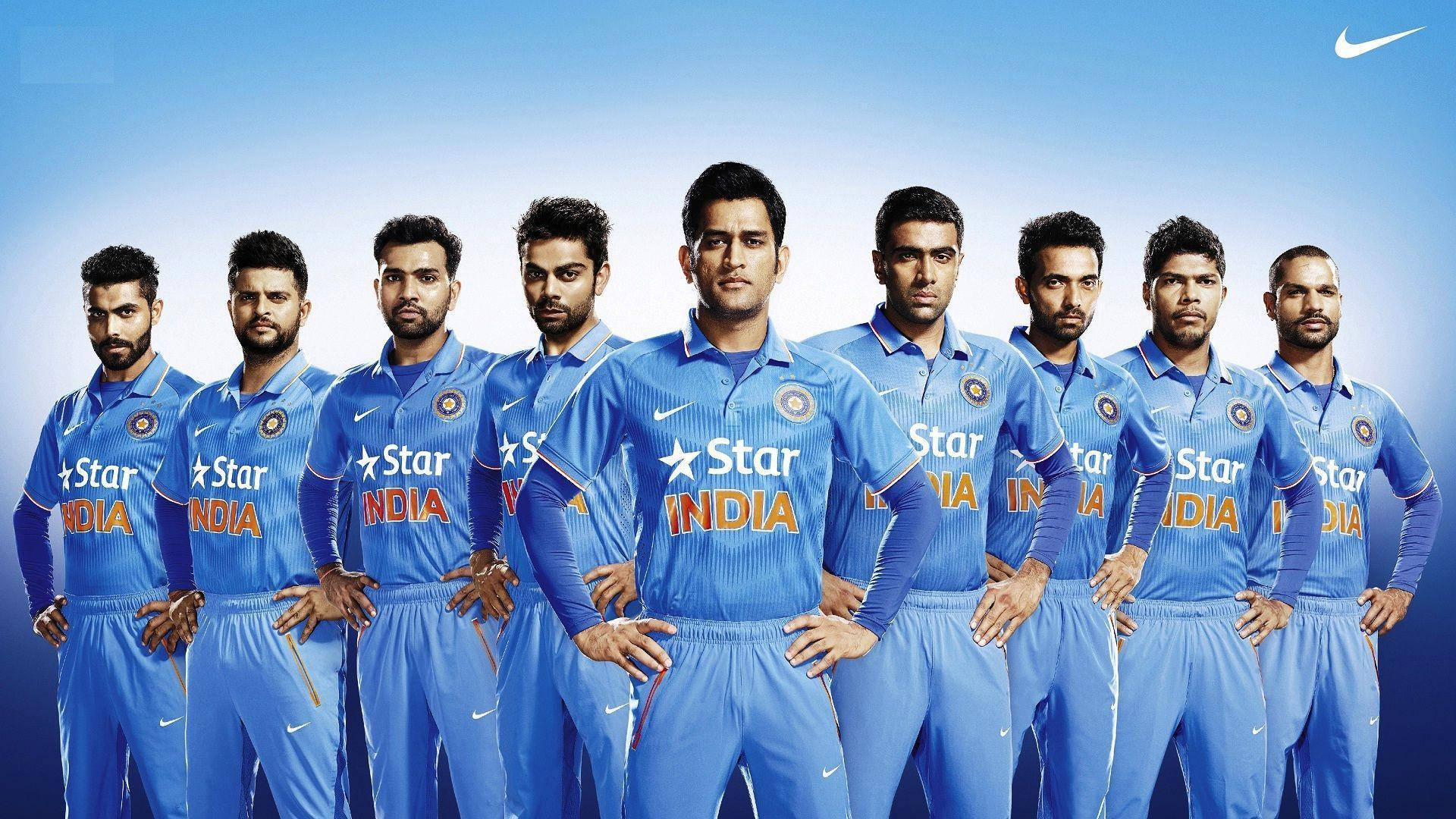Ms Dhoni 桌布 壁紙 — 印度板球隊身穿藍色制服，自信地站在帶有Nike和Star India標誌的漸變藍色背景前。