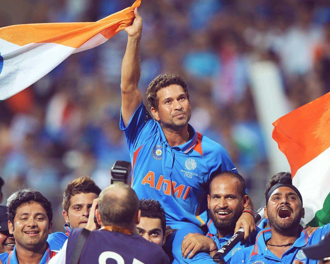 Sachin Tendulkar 桌布 壁紙 — 印度板球隊隊長沙欽·坦杜卡 Triumphantly 高舉國家的三色旗，隊友們在體育場人群中慶祝勝利。