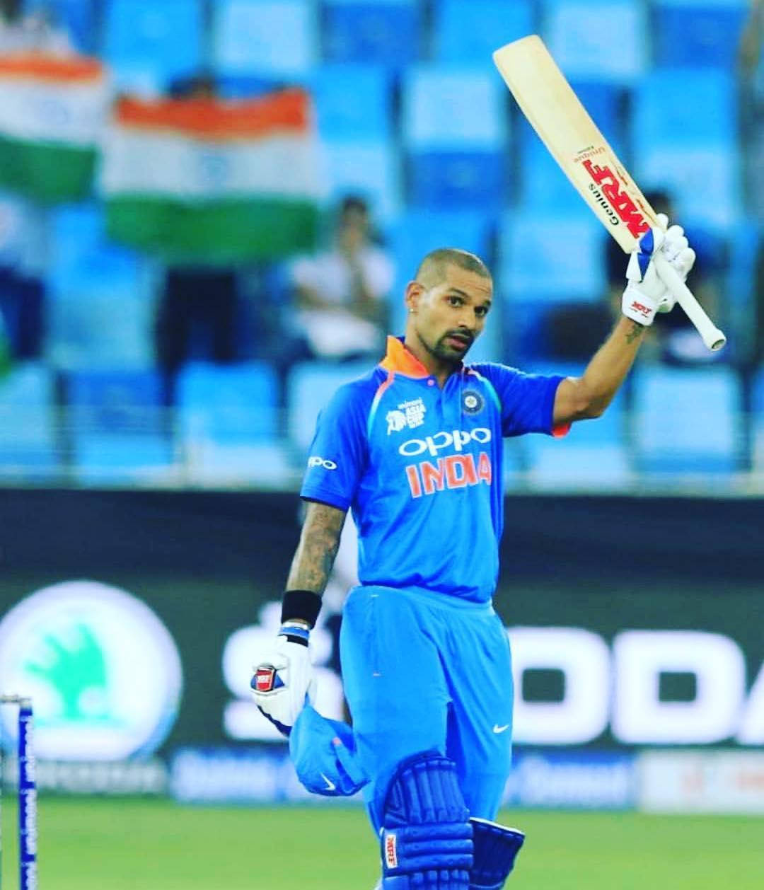 shikhar dhawan 桌布 壁紙 — 印度板球隊隊長維拉特·科利身穿藍色制服，在明亮的燈光下於球場上高舉球棒，展現勝利姿態。