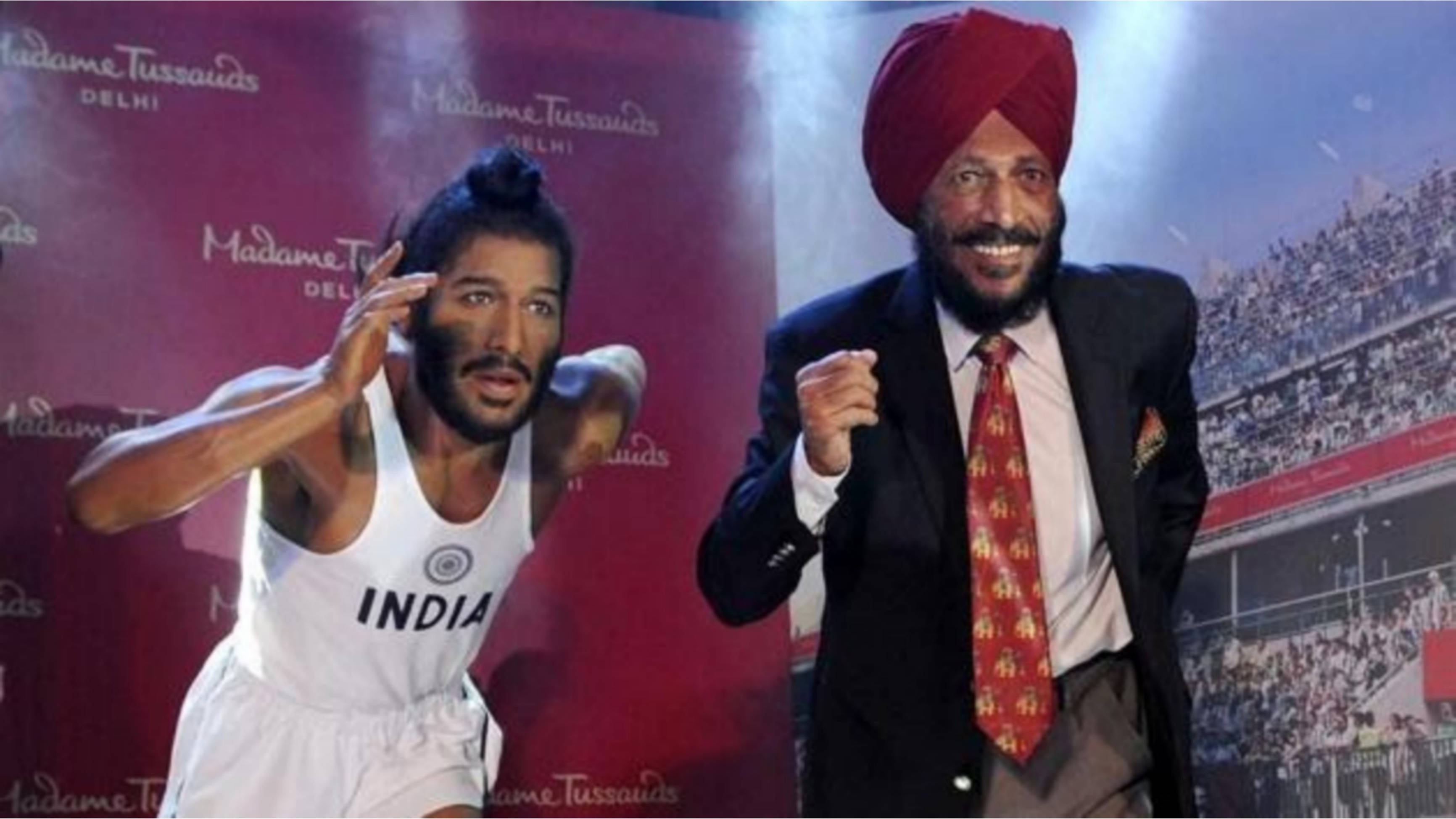 Milkha Singh 桌布 壁紙 — 印度運動員 Shikhar Dhawan 的蠟像身穿白色球衣，在德里杜莎夫人蠟像館與一位戴紅色頭巾、穿西裝的微笑男子並排擺姿勢。