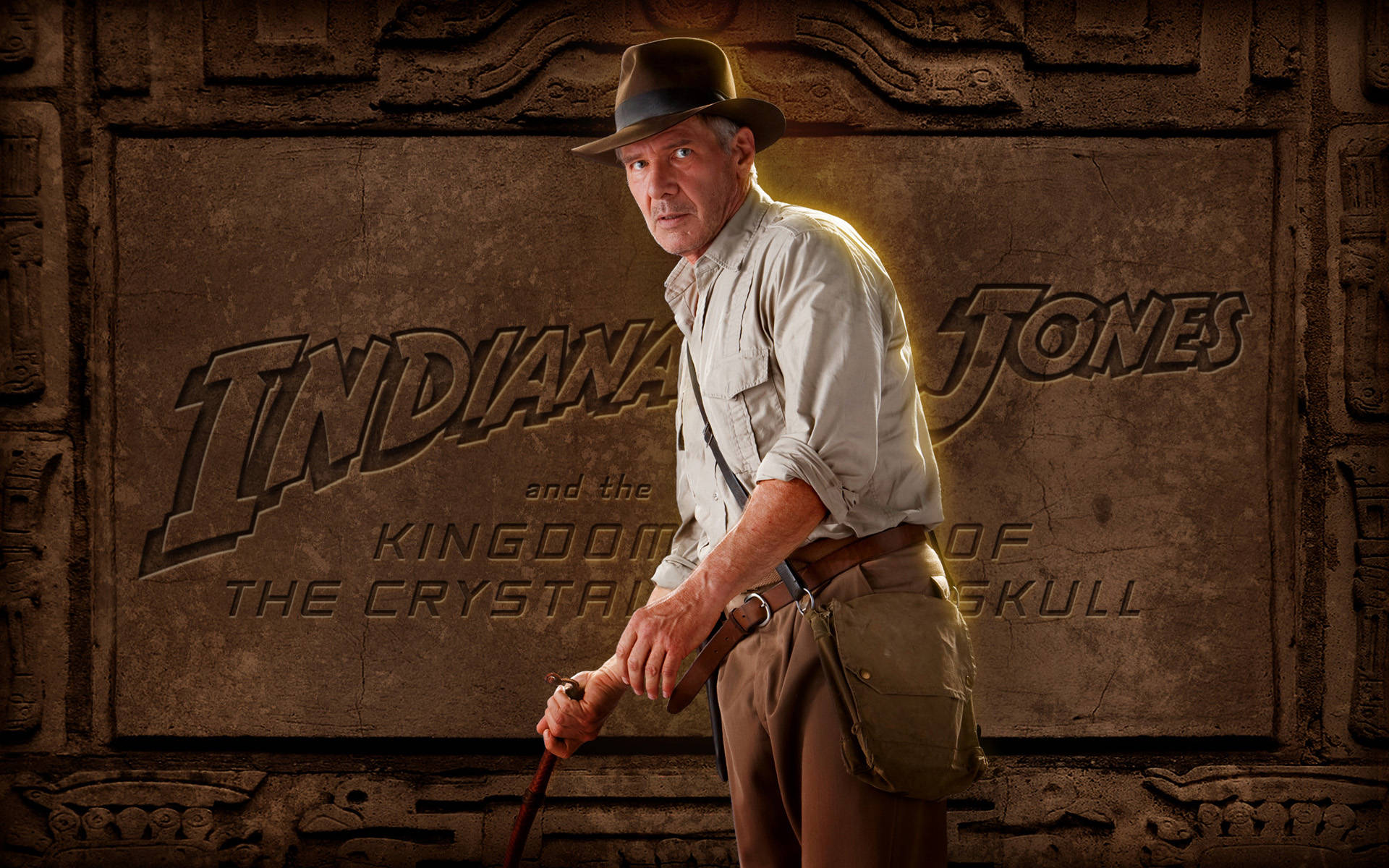 Indiana Jones 桌布 壁紙 — 印第安納瓊斯站在古老的石牆前，戴著標誌性的帽子和鞭子，並以電影標題為框。