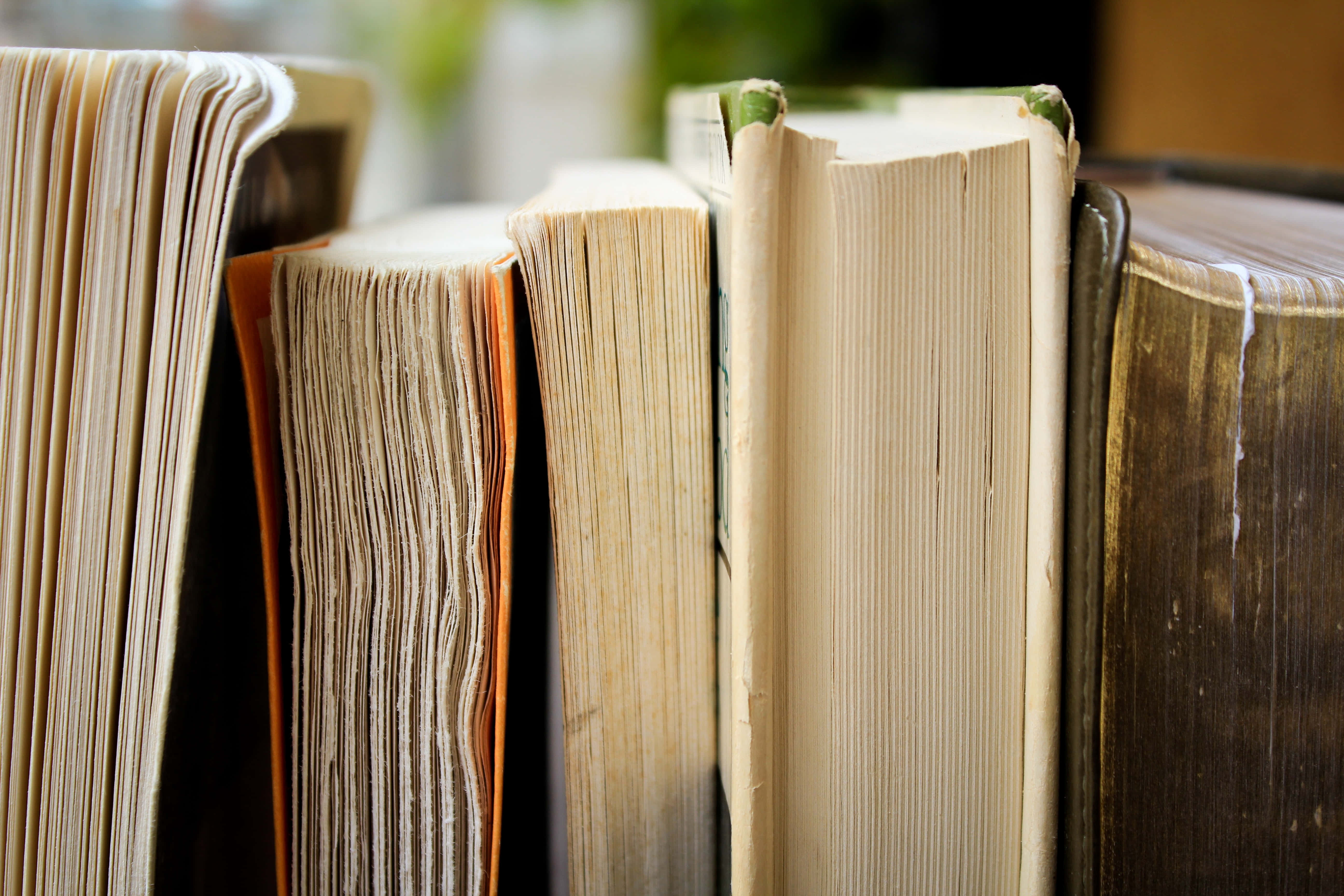 literature 桌布 壁紙 — 厚書直立的特寫，書脊磨損，泛黃的書頁捕捉柔和光線。