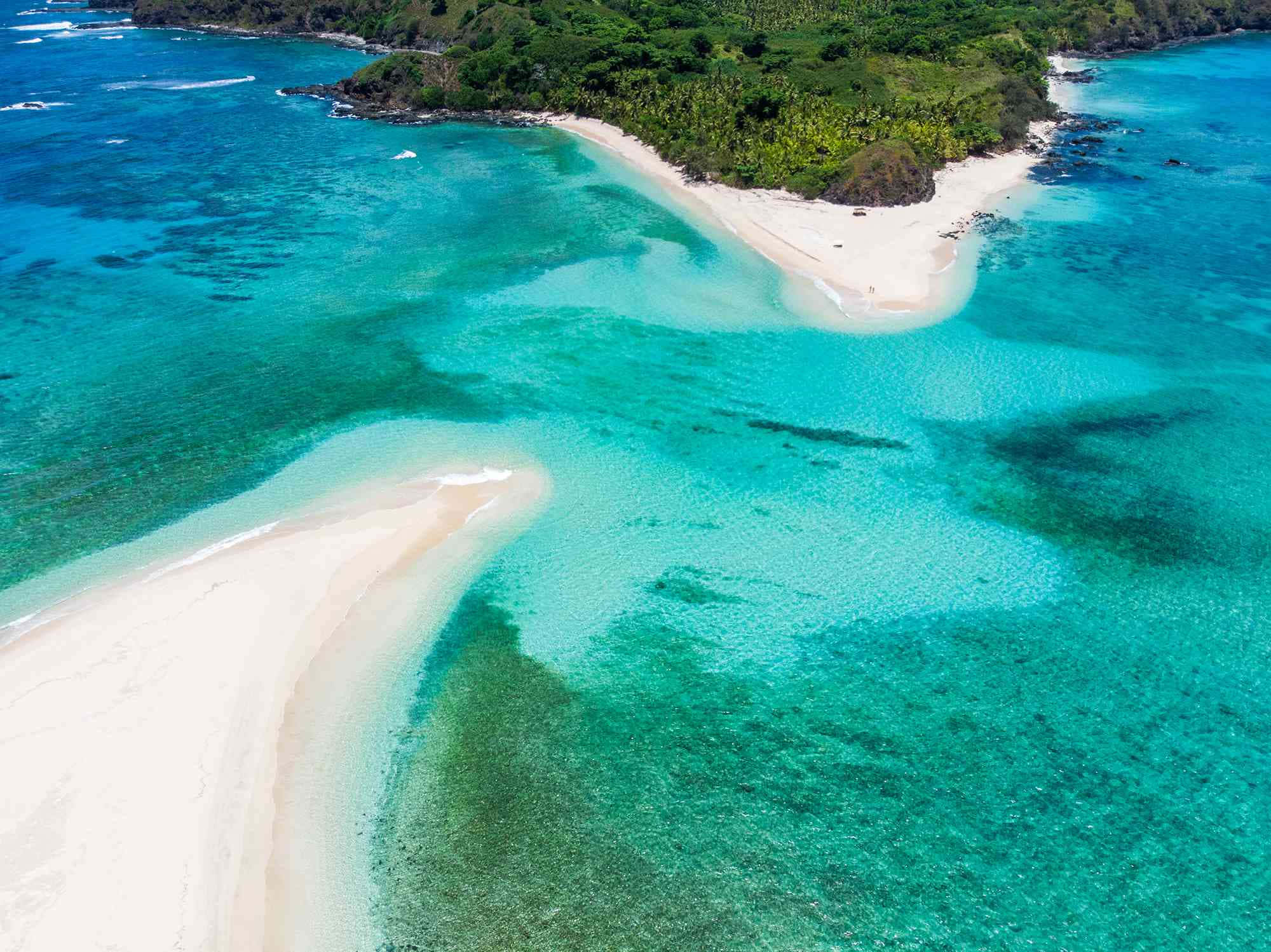 Fiji Beach 桌布 壁紙 — 原始熱帶島嶼的鳥瞰圖，擁有碧綠的海水和白色沙灘，周圍環繞著茂密的綠色植物。