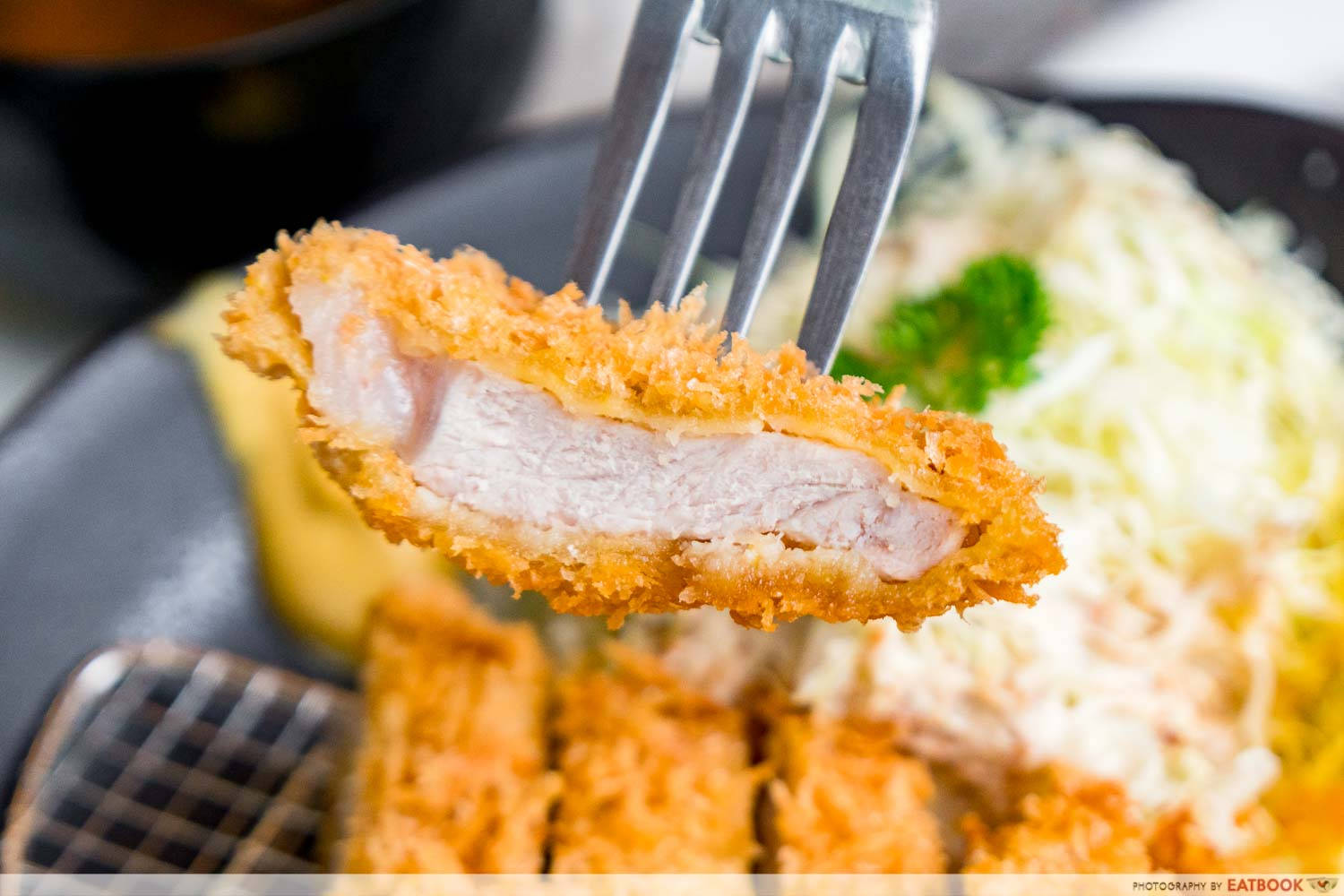 Food Photography 桌布 壁紙 — 叉子叉起一塊金黃酥脆的炸豬排，露出底下粉嫩多汁的肉和奶油醬汁的特寫。
