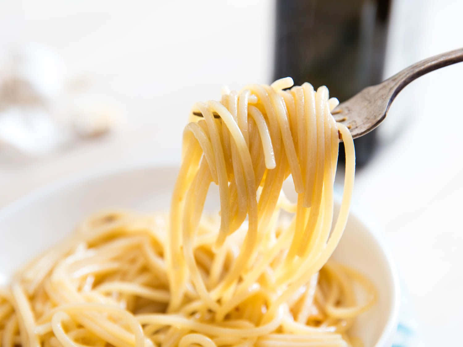 Noodles 桌布 壁紙 — 叉子從白色碗中提起光澤的義大利麵條，背景柔和模糊。