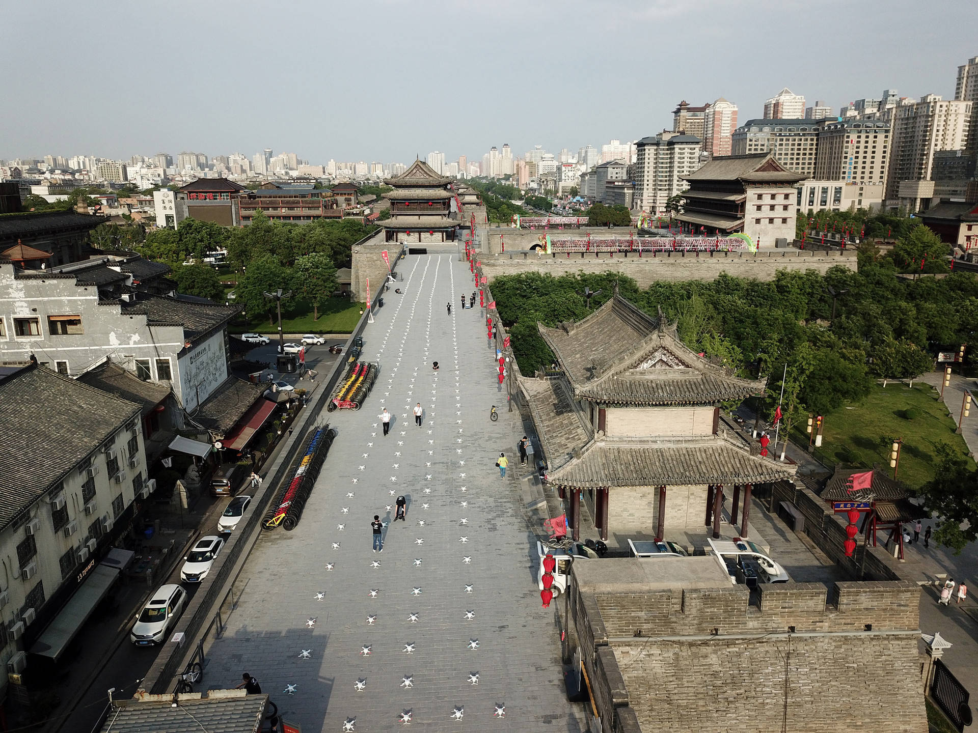 Xian 桌布 壁紙 — 古代中國城牆的鳥瞰圖，遊客沿著鋪砌的小路行走，兩旁是傳統建築和現代建築，天空朦朧。