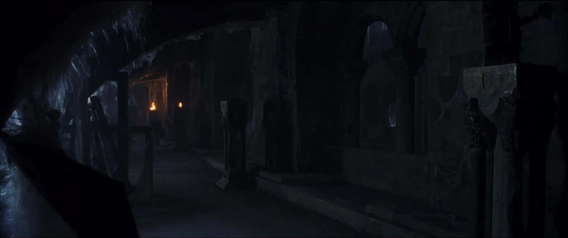 The Hogwarts Forbidden Corridor 桌布 壁紙 — 古代廢墟中一條光線昏暗的石頭走廊，搖曳的火把在 crumbling 的牆壁上投下詭異的陰影。