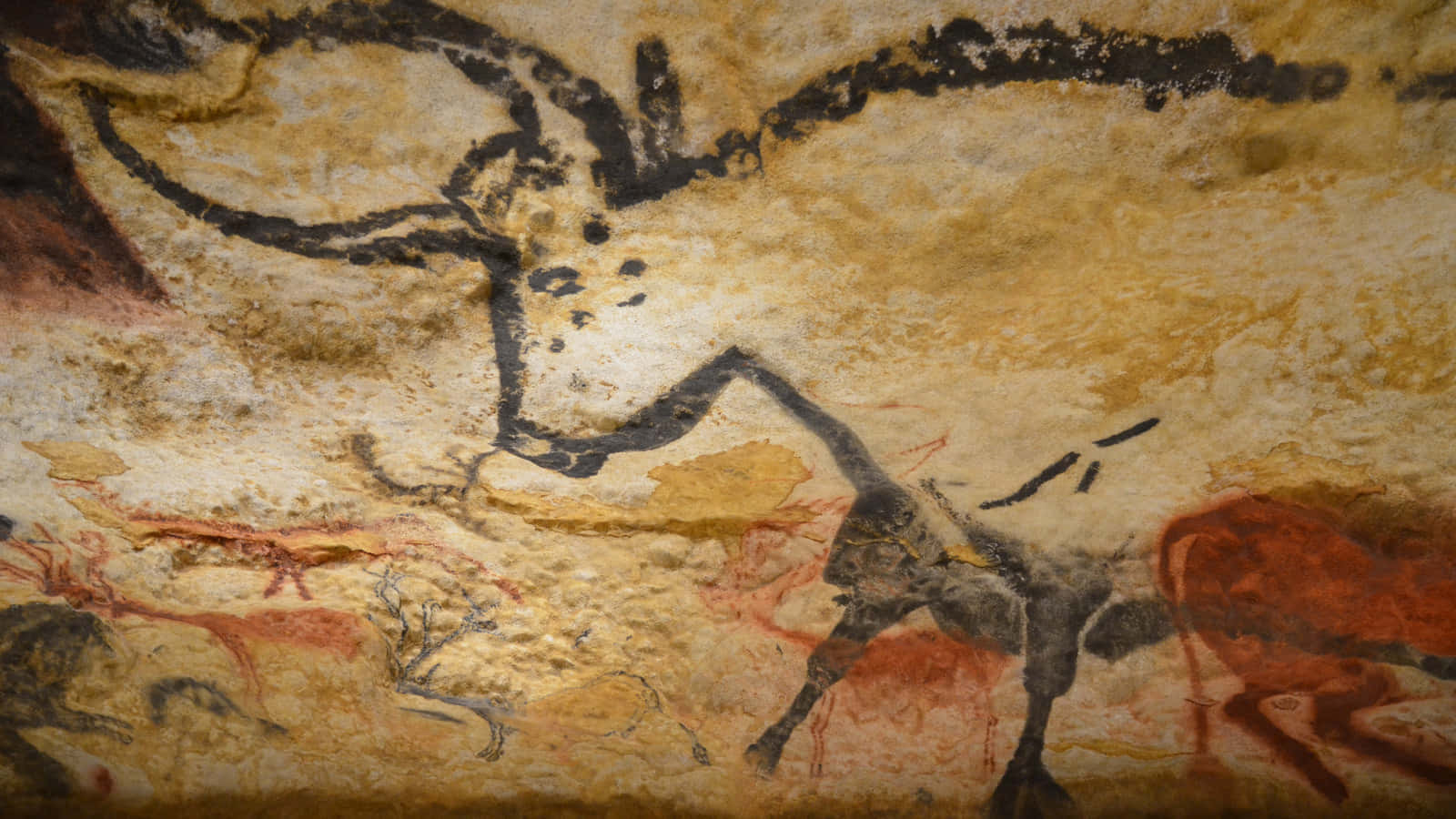 Lascaux Caves 桌布 壁紙 — 古代洞穴壁畫描繪了一隻黑色輪廓的大型野牛，帶有紅色赭石色調，位於紋理米色石頭上。