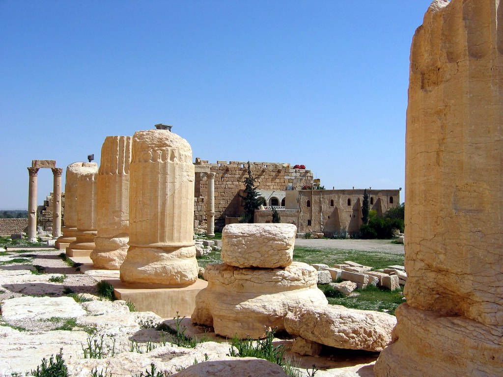 Syria 桌布 壁紙 — 古代石柱和廢墟在晴朗的藍天下，矗立在陽光明媚的考古遺址中。