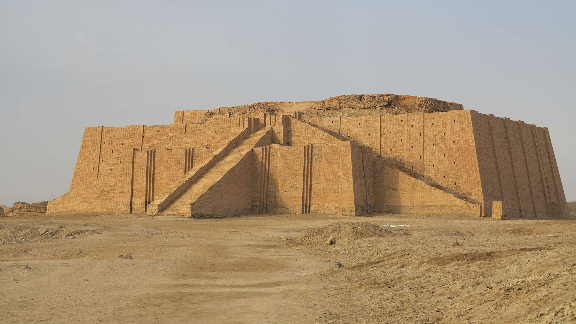 鄉村 桌布 壁紙 — 古代金字形神塔在乾旱沙漠中高聳，蒼白天空下，陽光照射的磚層和沙質前景。