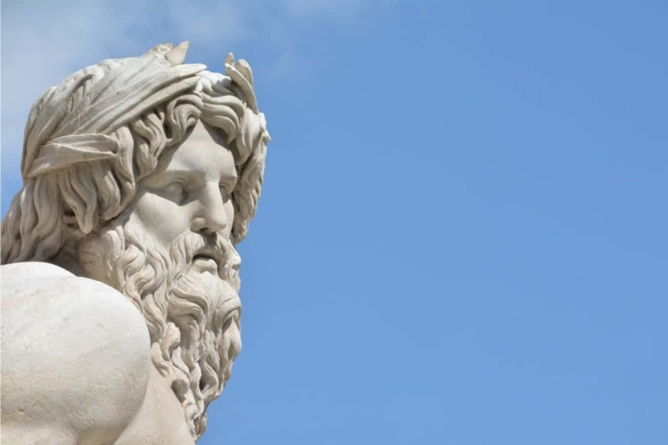 greek 桌布 壁紙 — 古典大理石鬍鬚男子戴月桂花冠雕像特寫，背景是晴朗藍天。