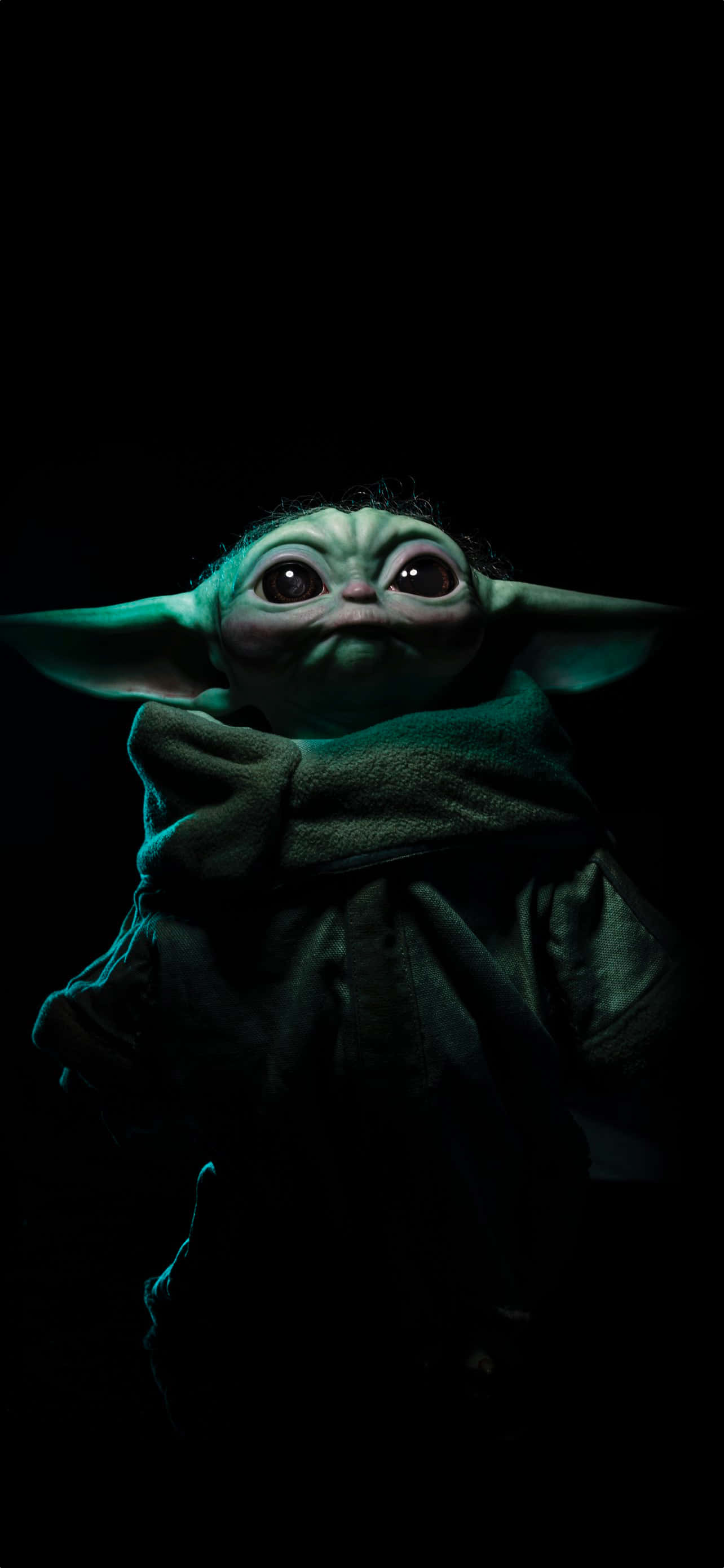 Baby Yoda iPhone 桌布 壁紙 — 古古近距離特寫，在漆黑背景中散發著青綠色光芒。