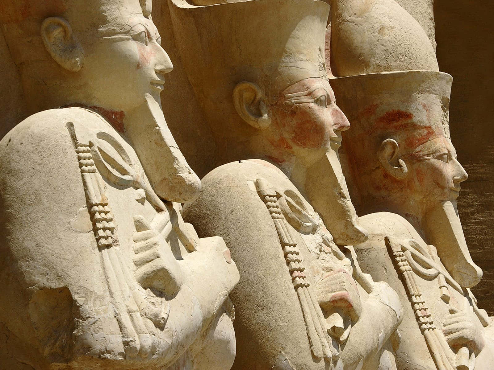 egyptian 桌布 壁紙 — 古埃及法老的石像，帶有彩繪面孔和儀式權杖，以側面雕刻。