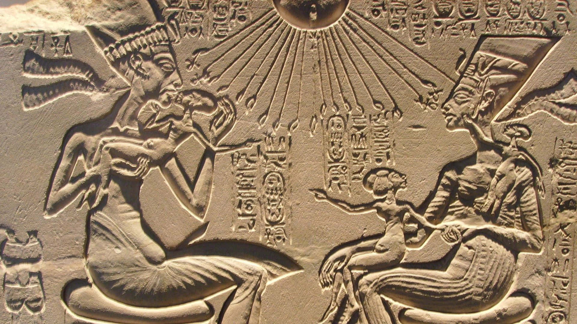 egyptian 桌布 壁紙 — 古埃及浮雕雕刻描繪了兩個坐著的人物，帶有象形文字和上方的太陽圓盤。