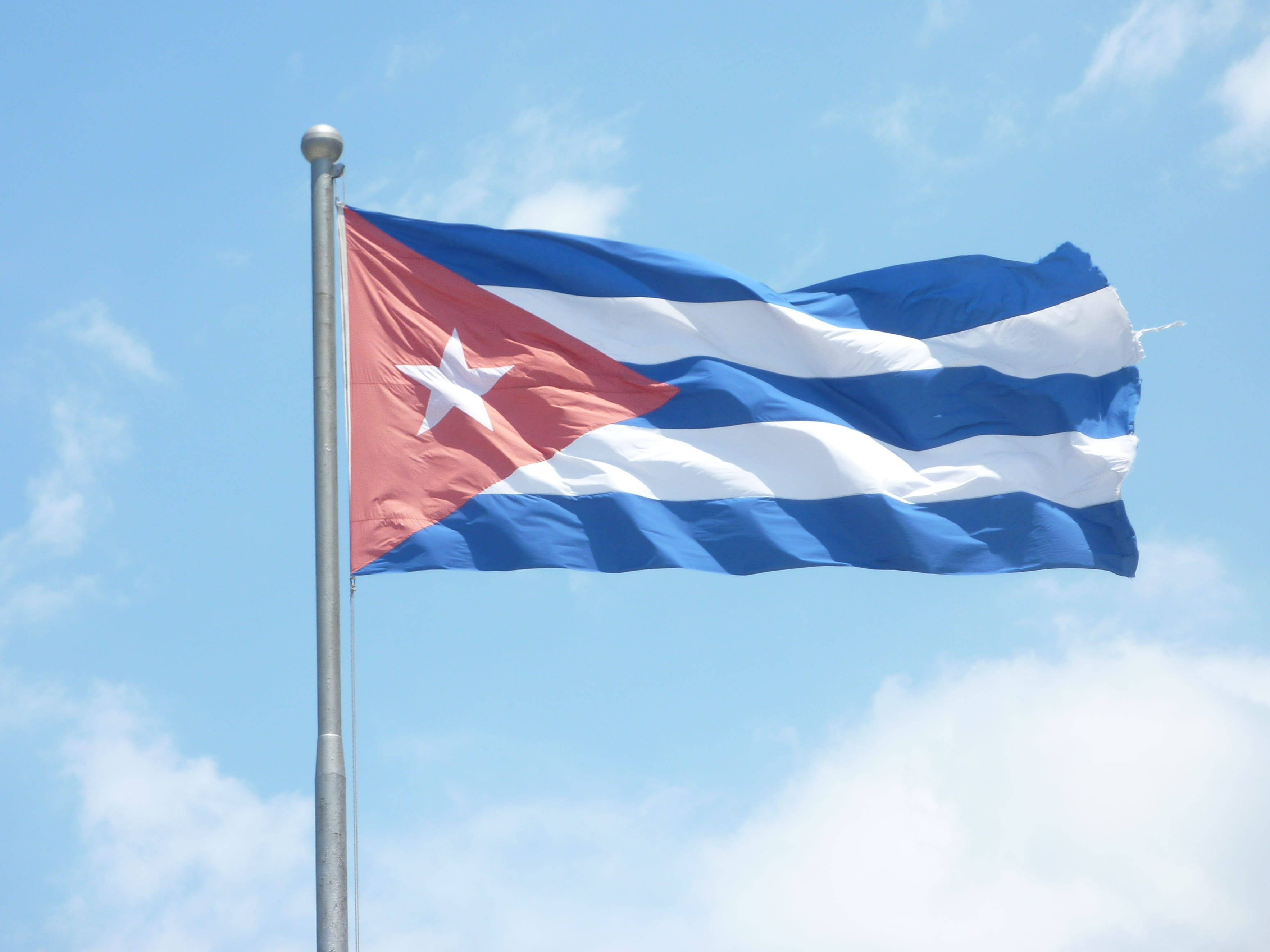 Cuban 桌布 壁紙 — 古巴國旗，帶有紅色三角形和白色星星，在藍天白雲中驕傲飄揚。