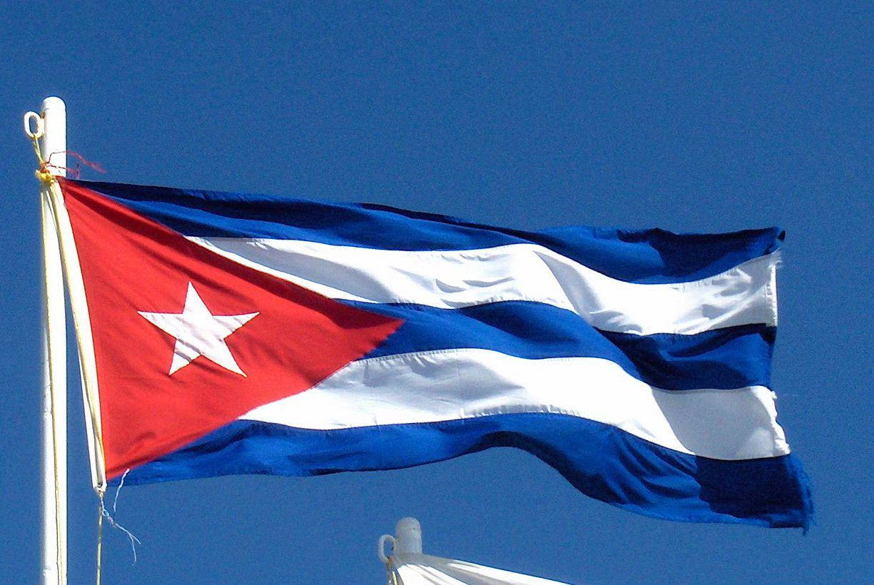 Cuban 桌布 壁紙 — 古巴國旗，帶有紅色三角形和白色星星，在清澈的藍天下自豪地飄揚。
