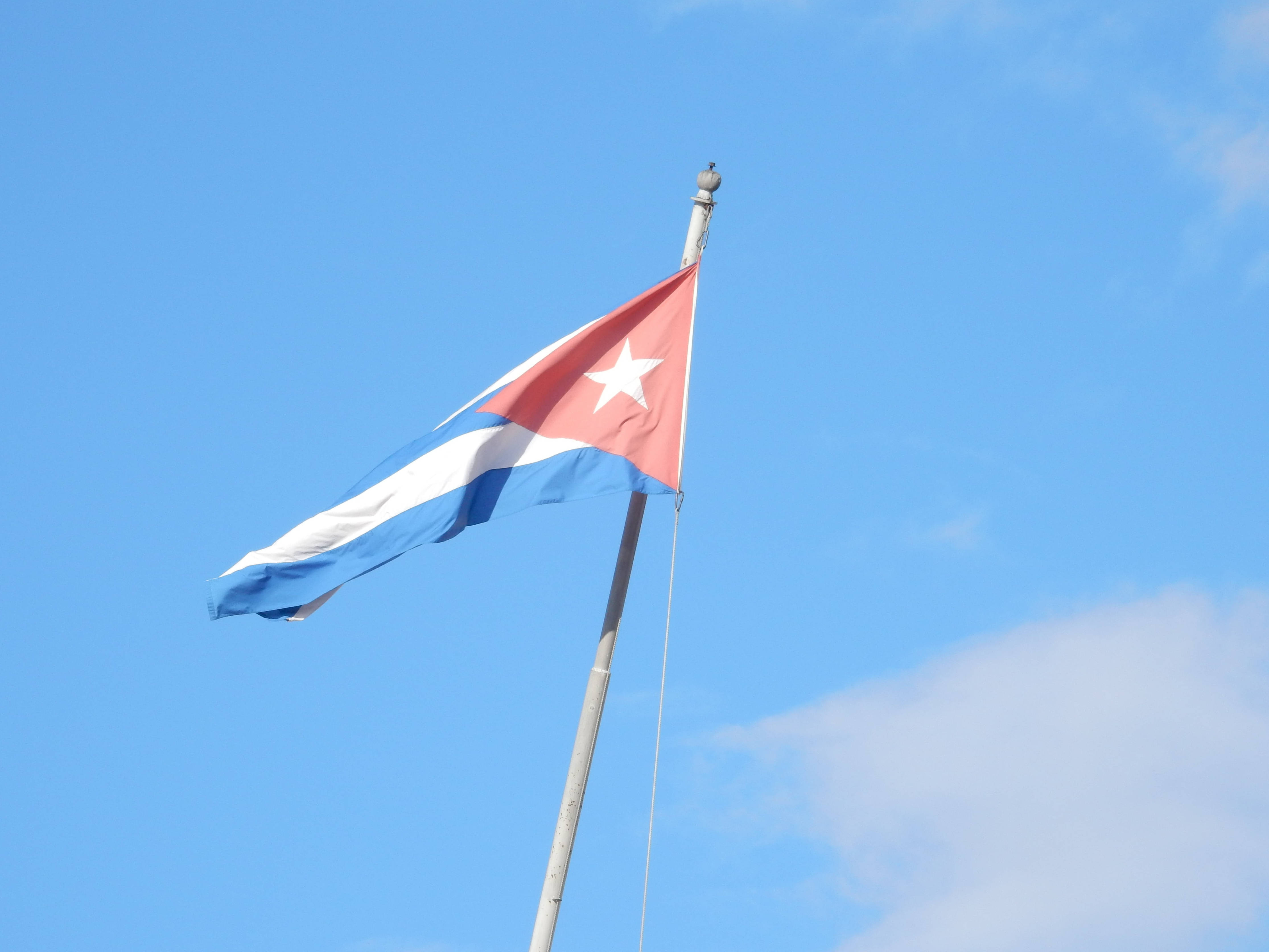Cuban 桌布 壁紙 — 古巴國旗，有紅、白、藍條紋和一顆白星，在晴朗的藍天下飄揚。