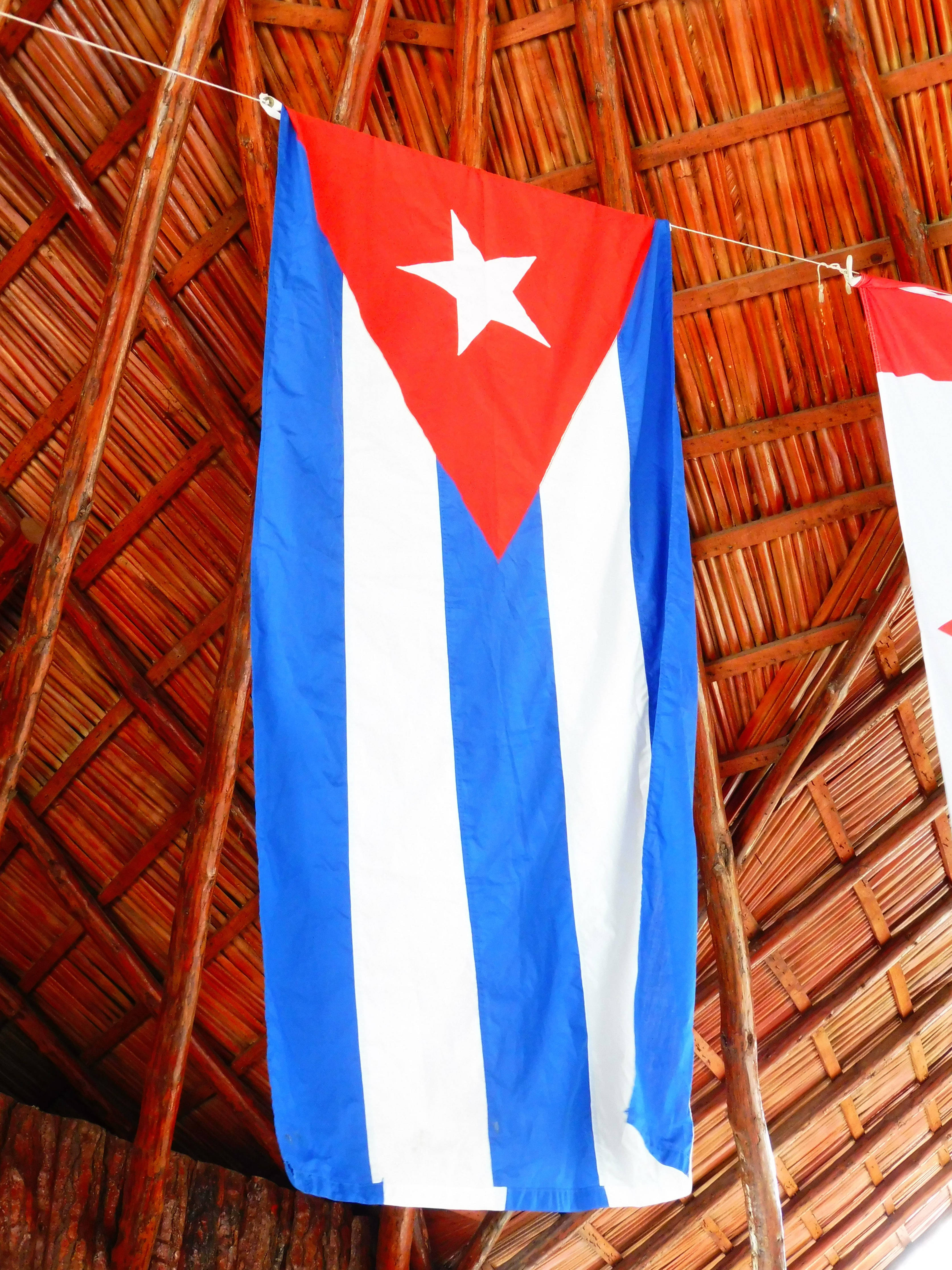 Cuban 桌布 壁紙 — 古巴國旗在質樸的茅草屋頂和溫暖的木樑上顯眼地懸掛著。