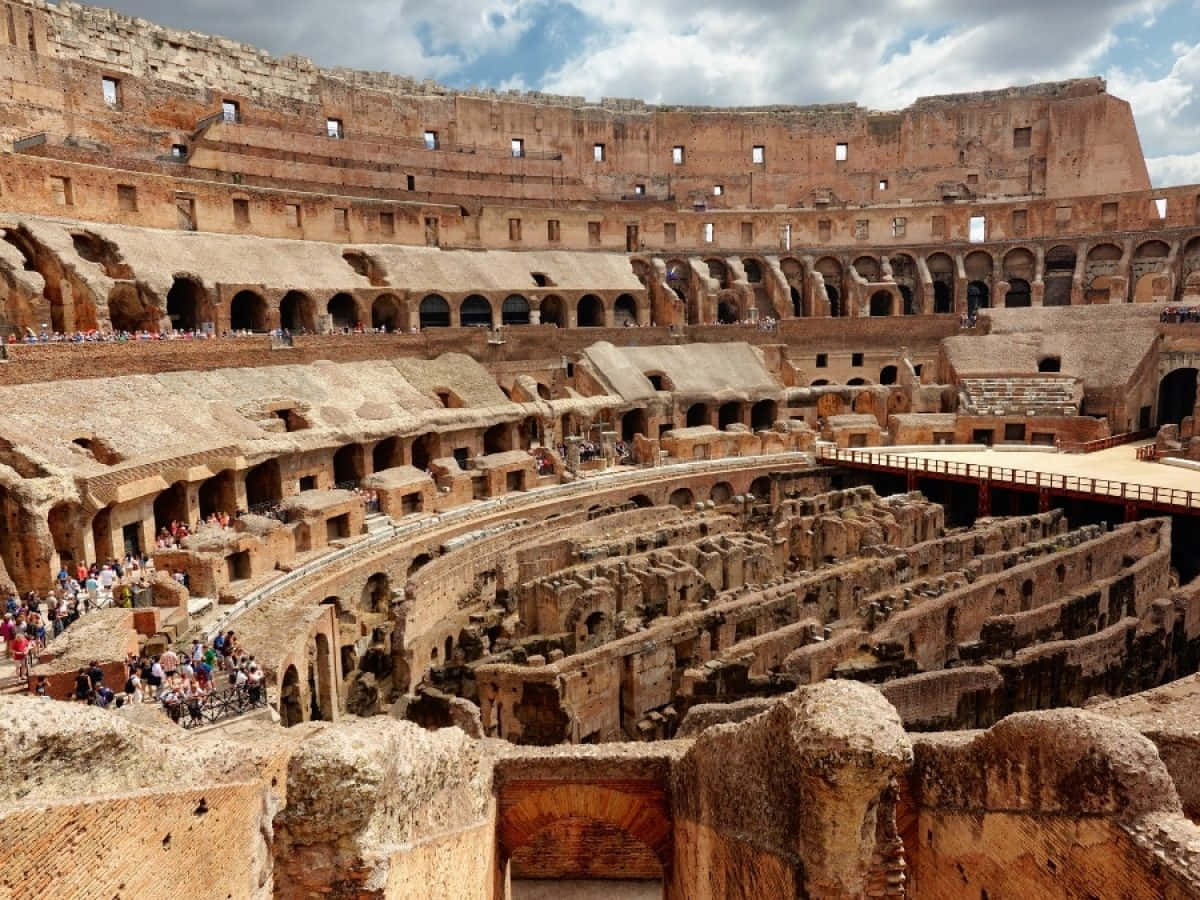 Roman Colosseum 桌布 壁紙 — 古羅馬競技場，遊客在部分多雲的天空下探索其巨大的石階。