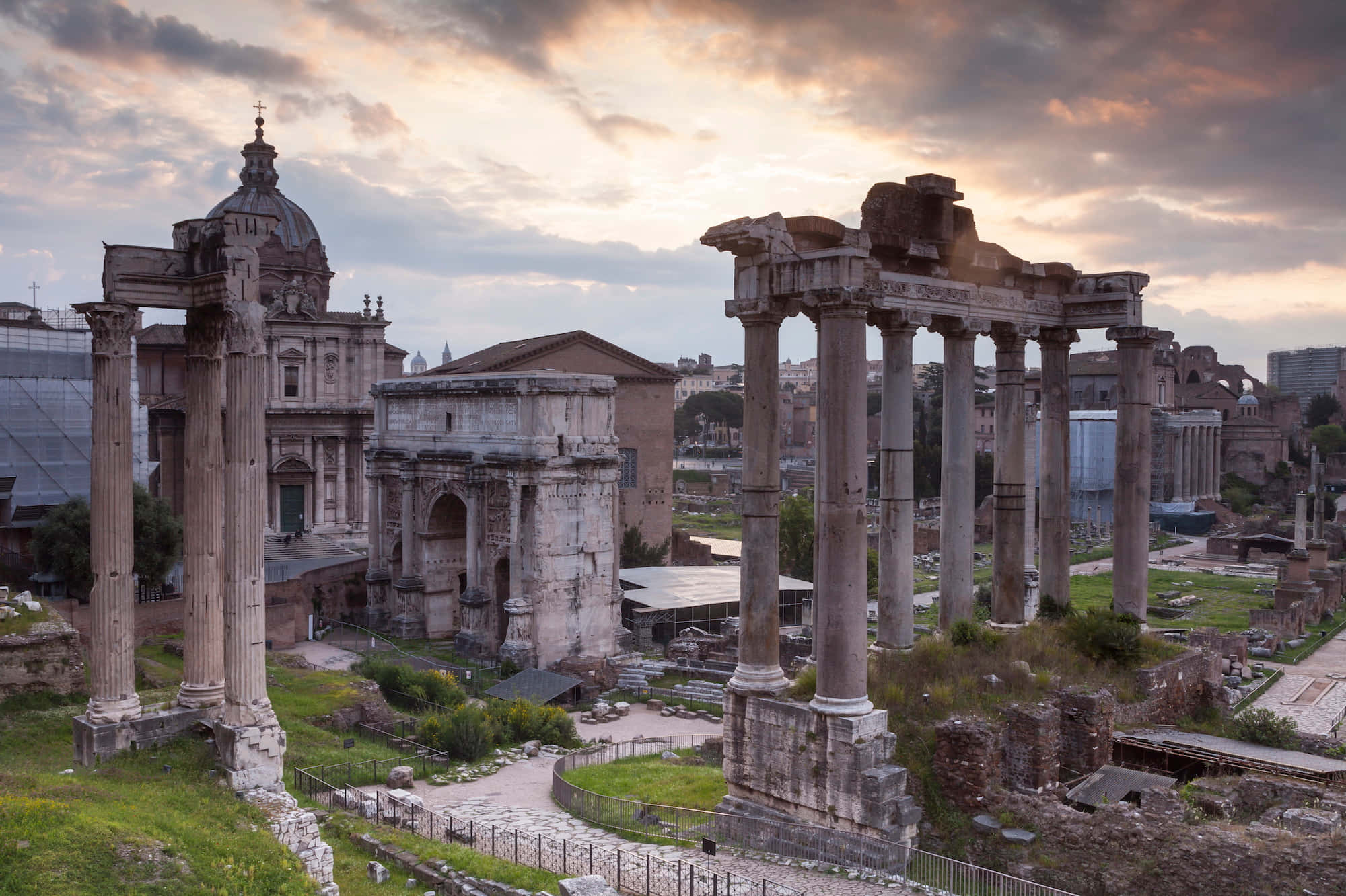 Roman Colosseum 桌布 壁紙 — 古羅馬遺跡，高聳的柱子和圓頂結構沐浴在金色的日落光芒中。