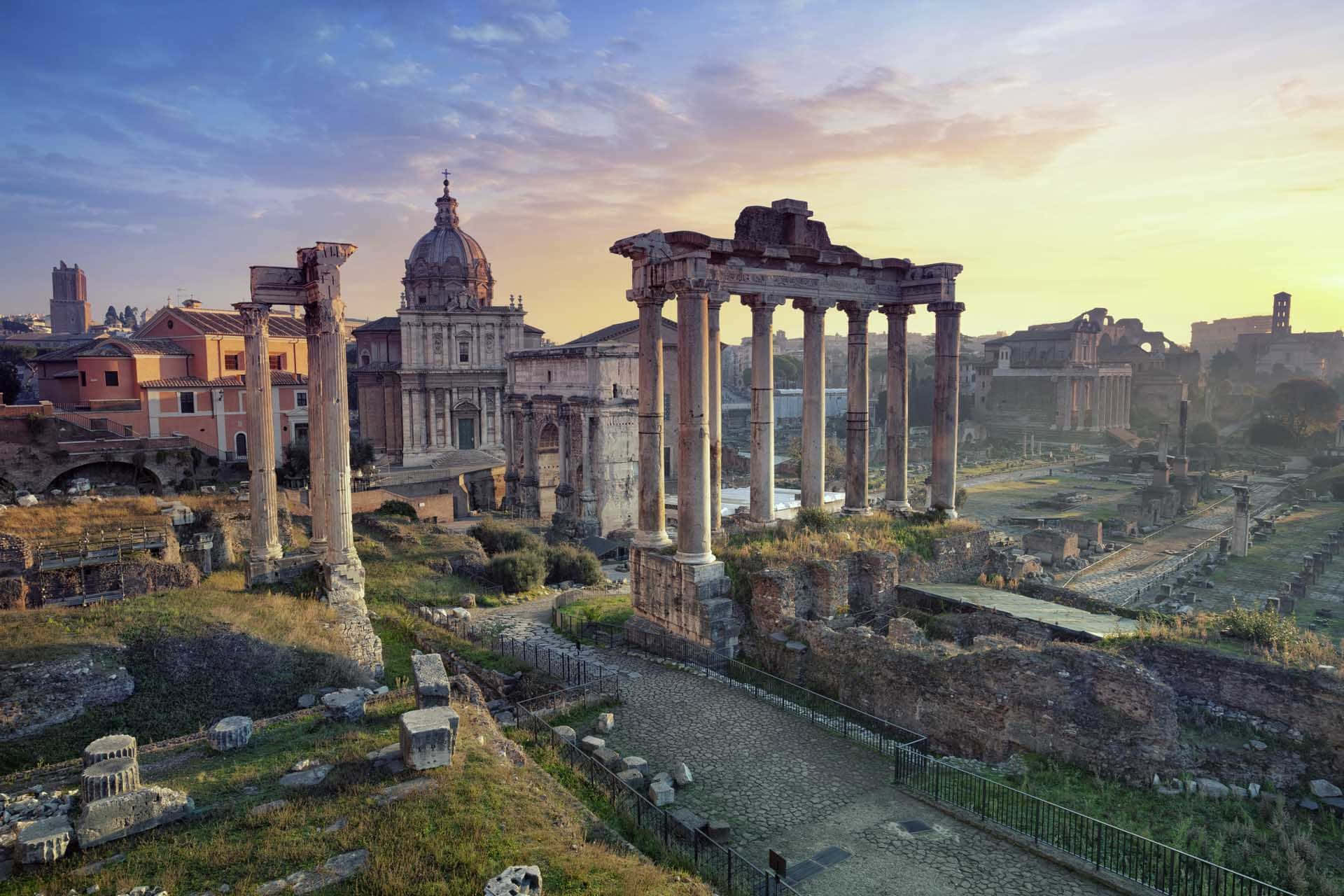 Roman 桌布 壁紙 — 古羅馬遺跡沐浴在金色夕陽中，豎立的柱子和背景中的圓頂教堂。