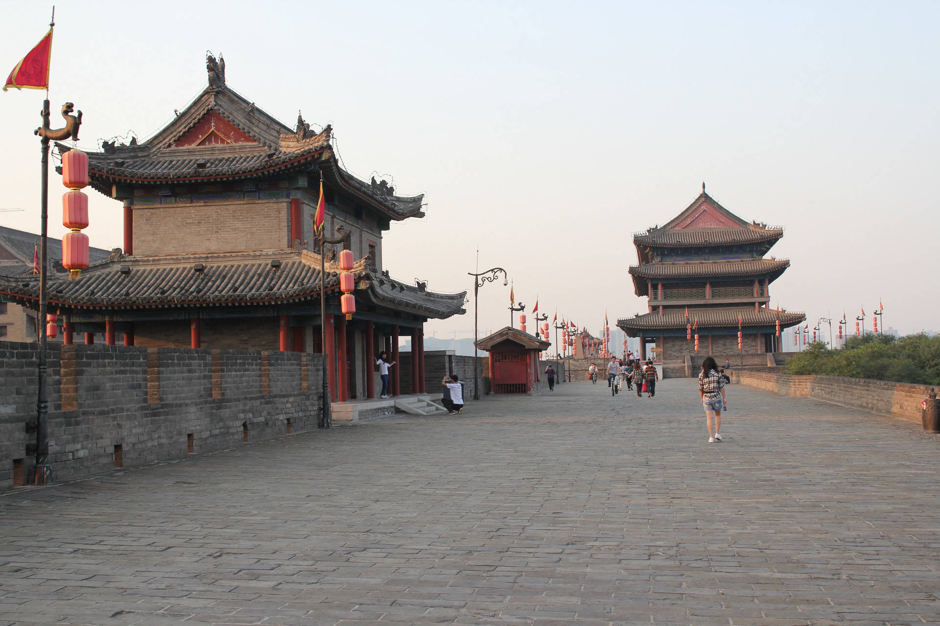 Xian 桌布 壁紙 — 古老的中國城牆，掛著紅燈籠，遊客在黃金時段沿著石徑行走。