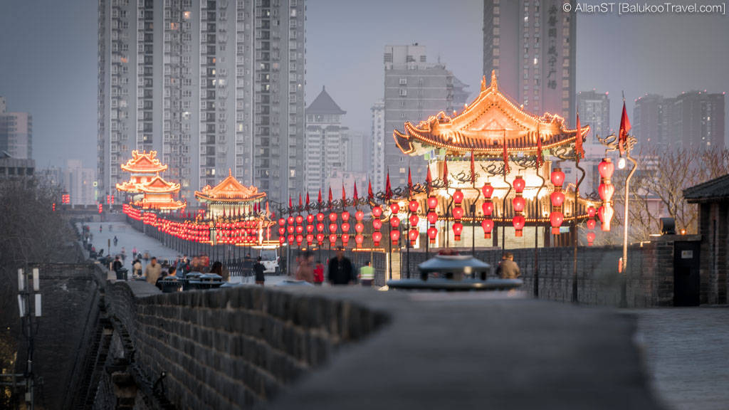 Xian 桌布 壁紙 — 古老的中國城牆在黃昏時被紅色燈籠照亮，現代摩天大樓在背景中若隱若現。