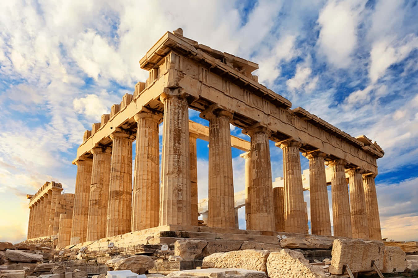 greek 桌布 壁紙 — 古老的帕德嫩神廟在湛藍的天空下雄偉矗立，蓬鬆的白雲在其風化的石柱上投下柔和的陰影。