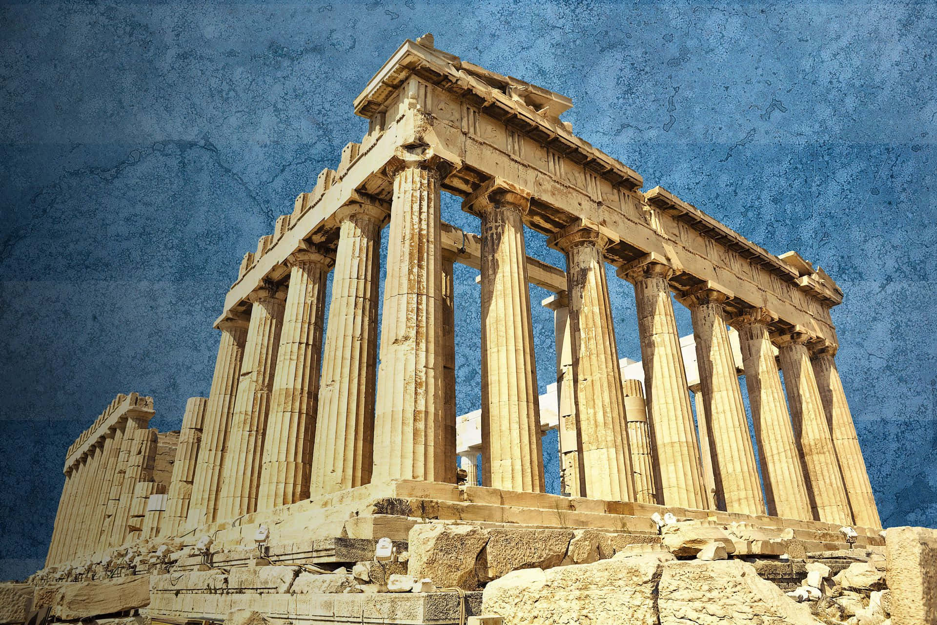 greek 桌布 壁紙 — 古老的帕德嫩神廟在質感藍天下雄偉矗立，金色石柱與風化遺跡相映成輝。