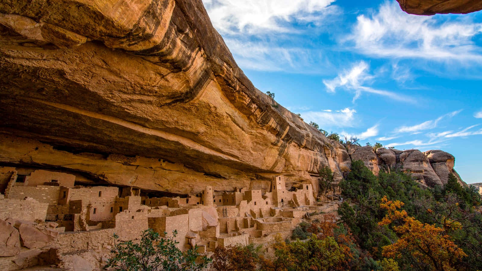 Colorado 桌布 壁紙 — 古老的懸崖住所普韋布洛建築，依偎在巨大的砂岩懸崖下，明亮的藍天中飄著縷縷白雲。