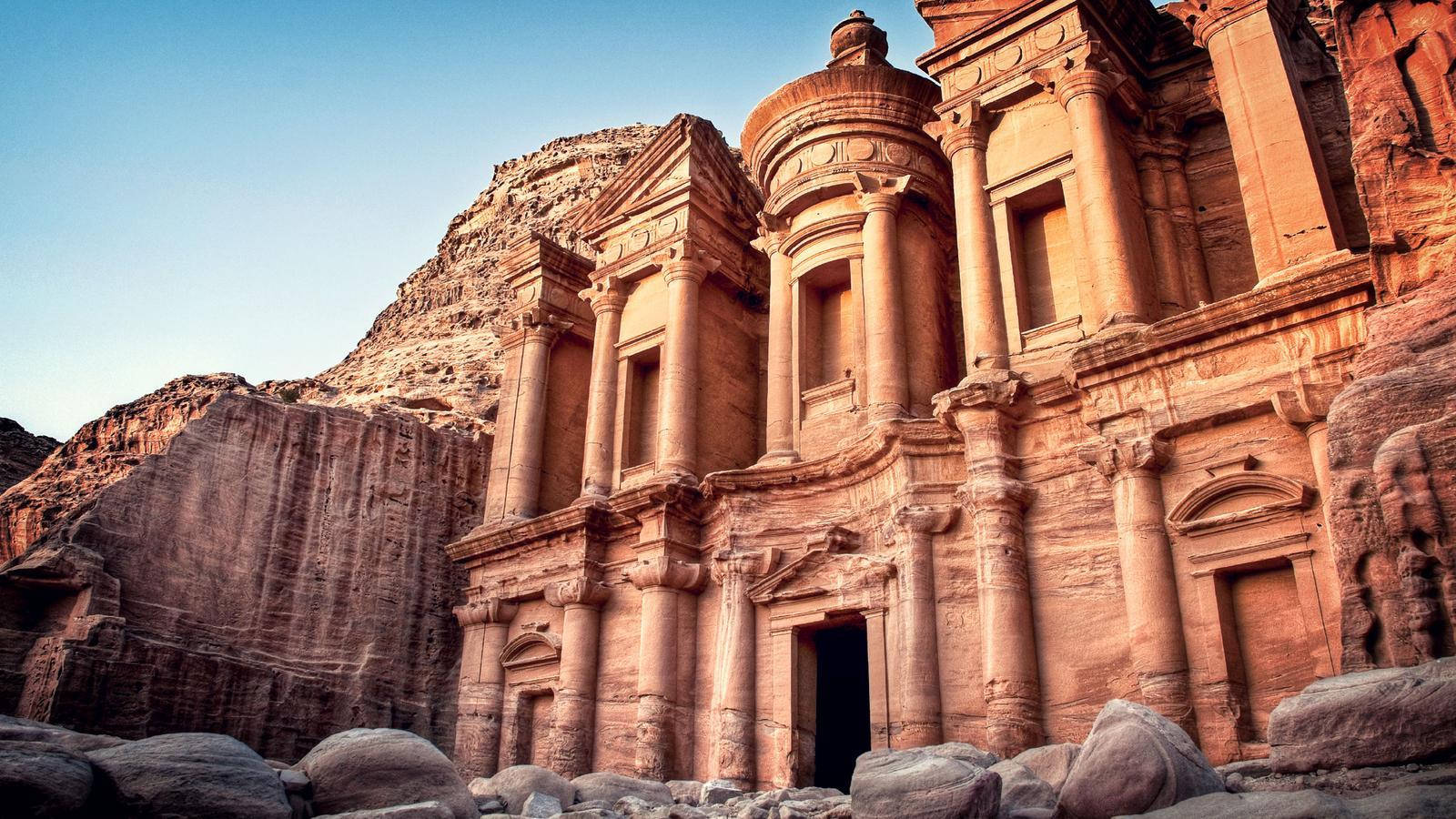 Jordan 桌布 壁紙 — 古老的玫瑰色石廟雕刻在沙漠懸崖上，沐浴在金色的日落光芒中。