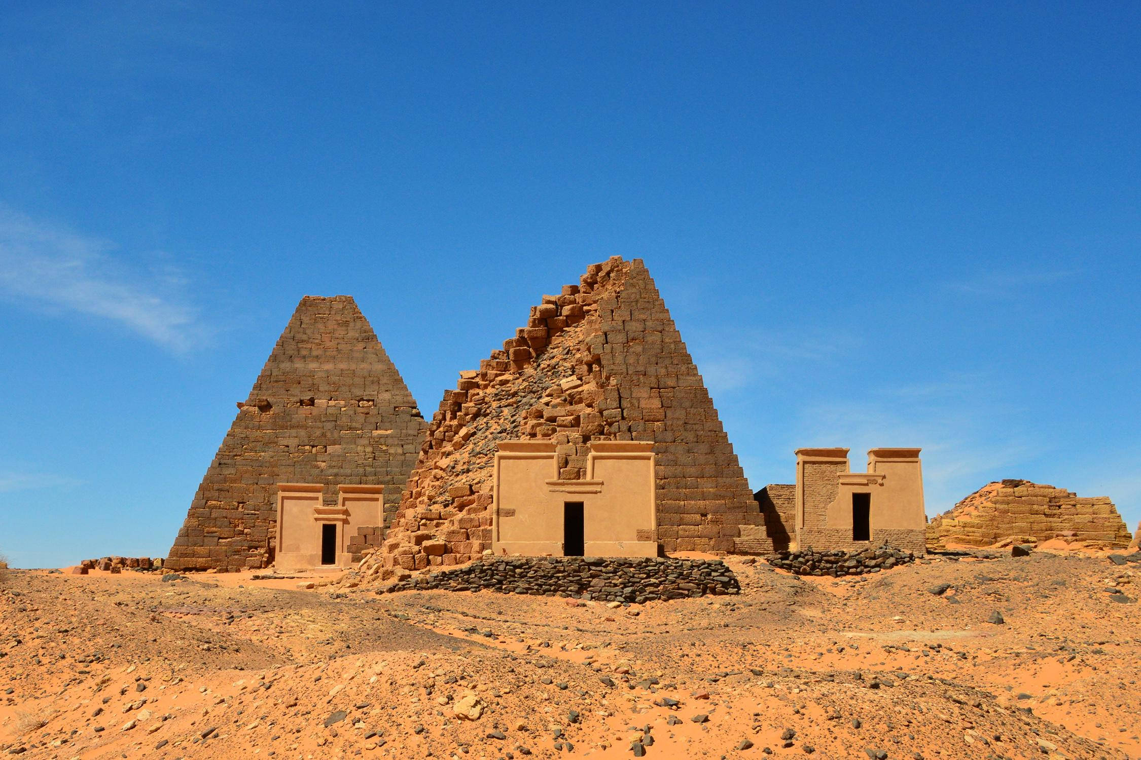 Sudan 桌布 壁紙 — 古老的石造金字塔在晴朗藍天下的廣闊沙漠中風化矗立。