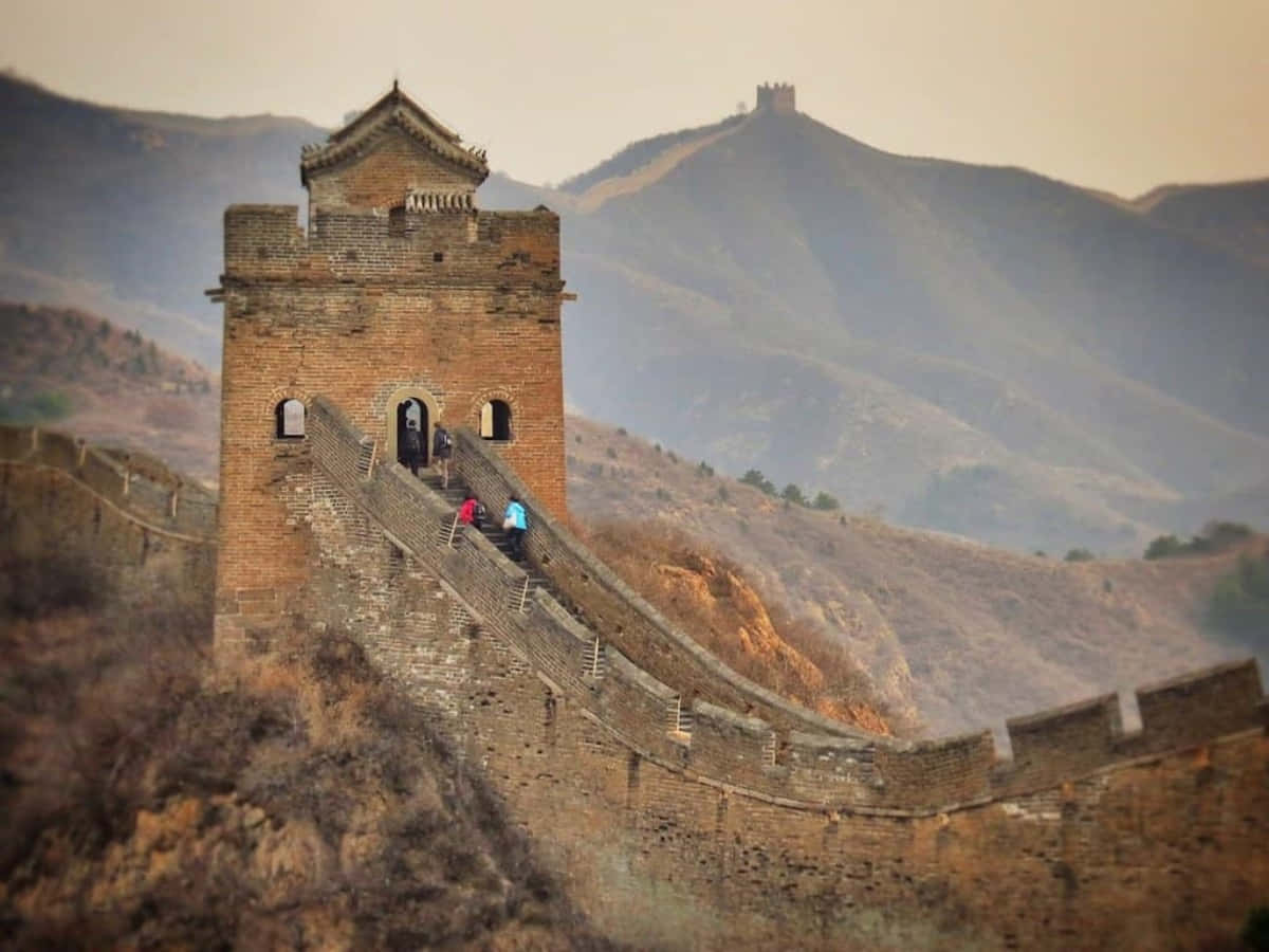 Asia 桌布 壁紙 — 古老的石造長城城樓在霧氣籠罩的山巒上聳立，細小的遠足者在崎嶇的道路上攀登。